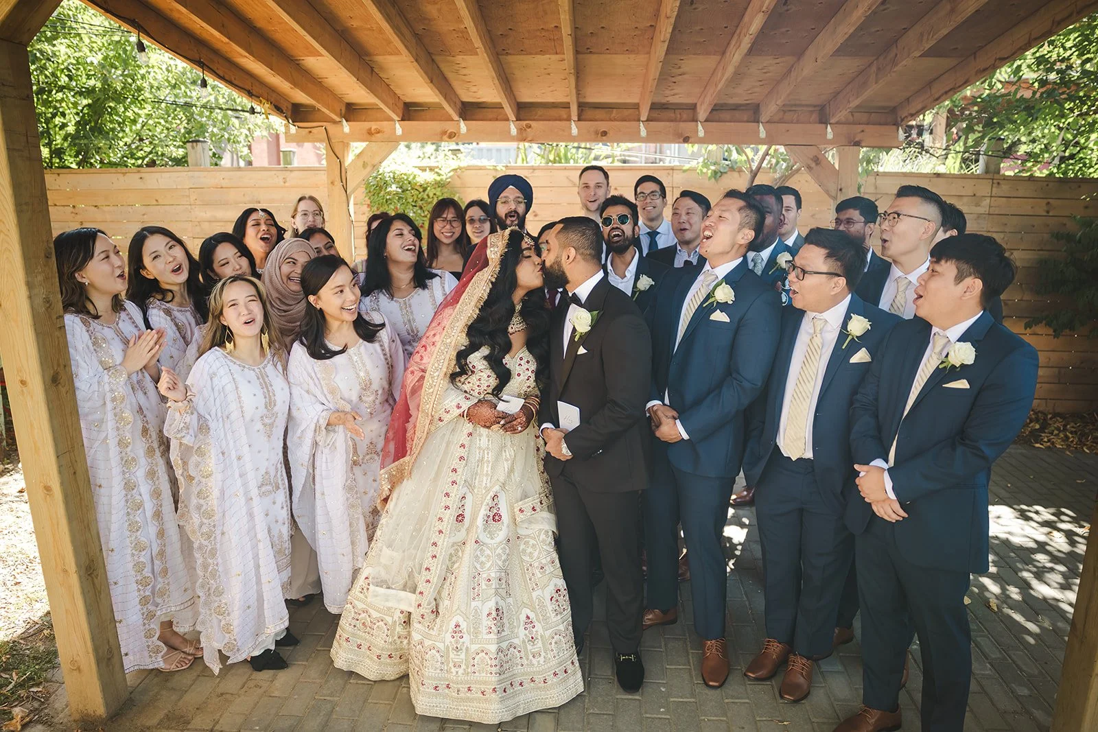 Bride and Groom kissing surrounded by family on wedding day  Hamilton, ON  Royal Hamilton Yacht Club  Fedora Media .jpg