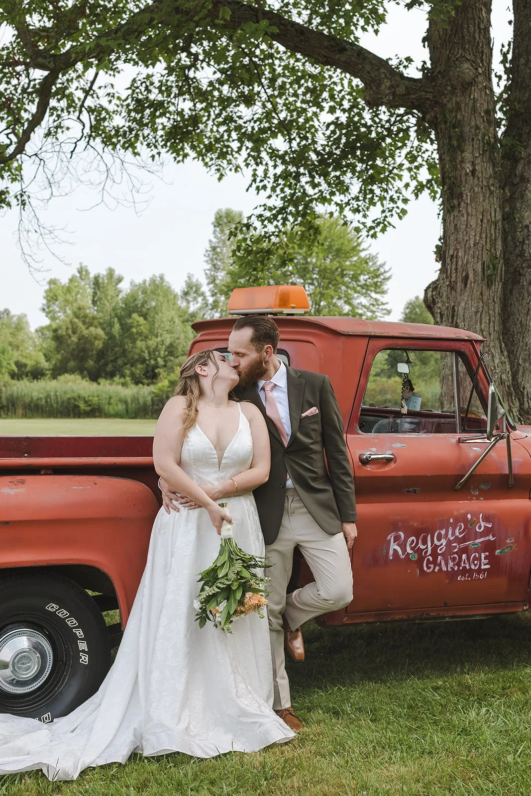 Bride and groom lean against truck while kissing  London, ON  Backyard Wedding  Fedora Media.jpg