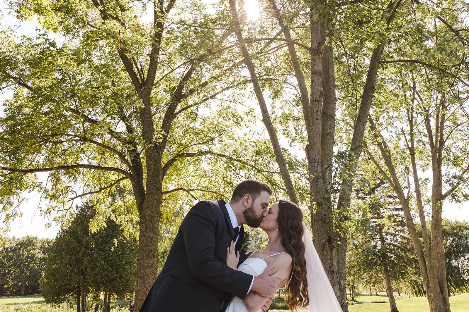 Bride and groom kiss surrounded by trees Century Pines  Fedora Media.jpg