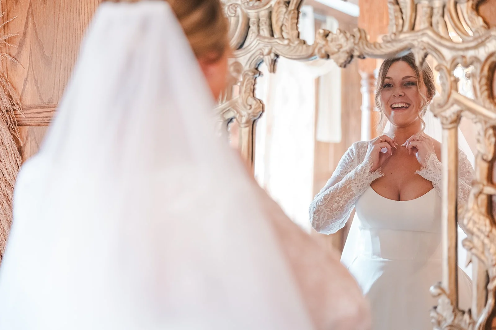 Smiling bride adjusting neclace in mirror  Erin Estates  Fedora Media.jpg