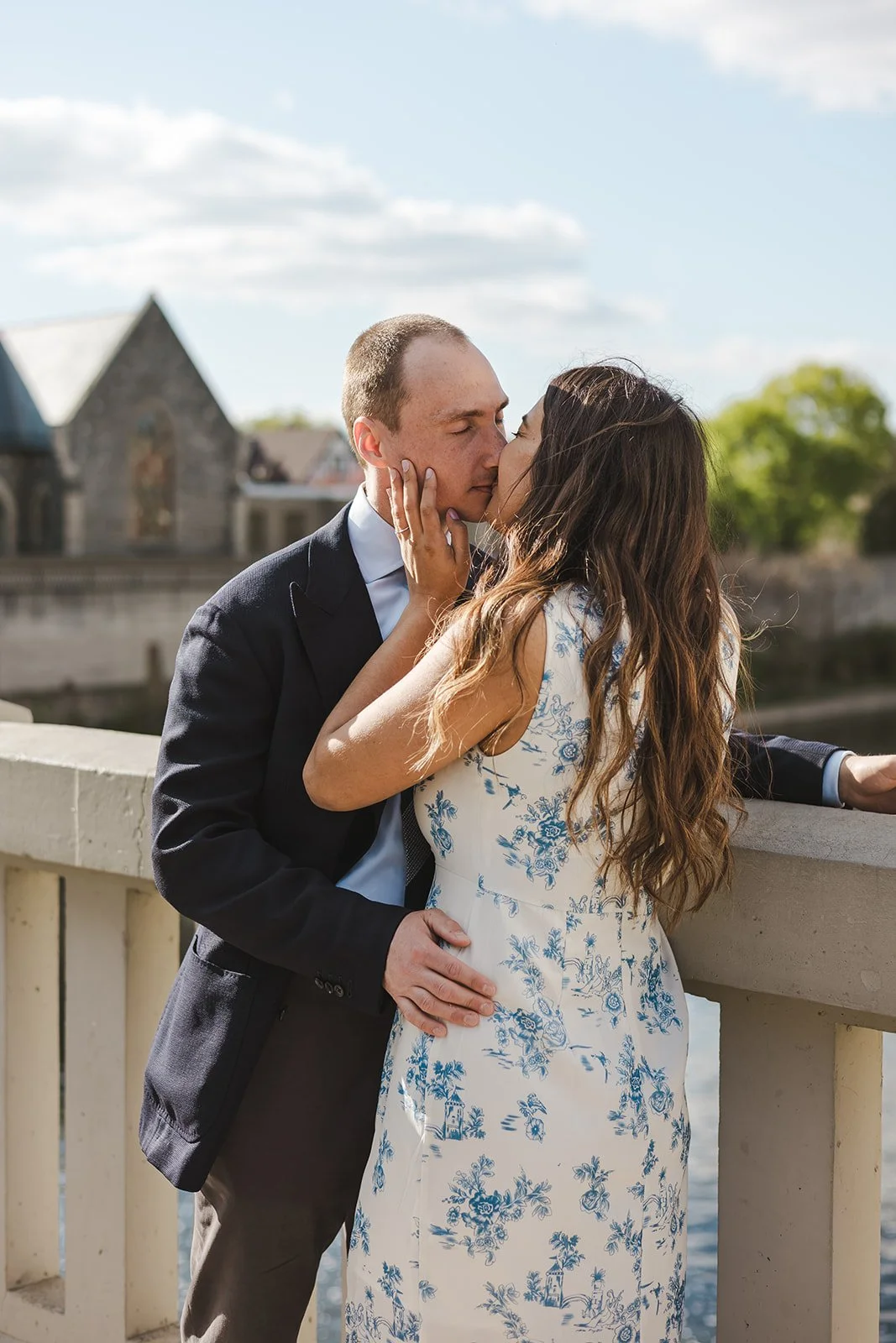Woman grabbing man's face as they kiss on bridge  Ontario Engagement  Fedora Media.jpg