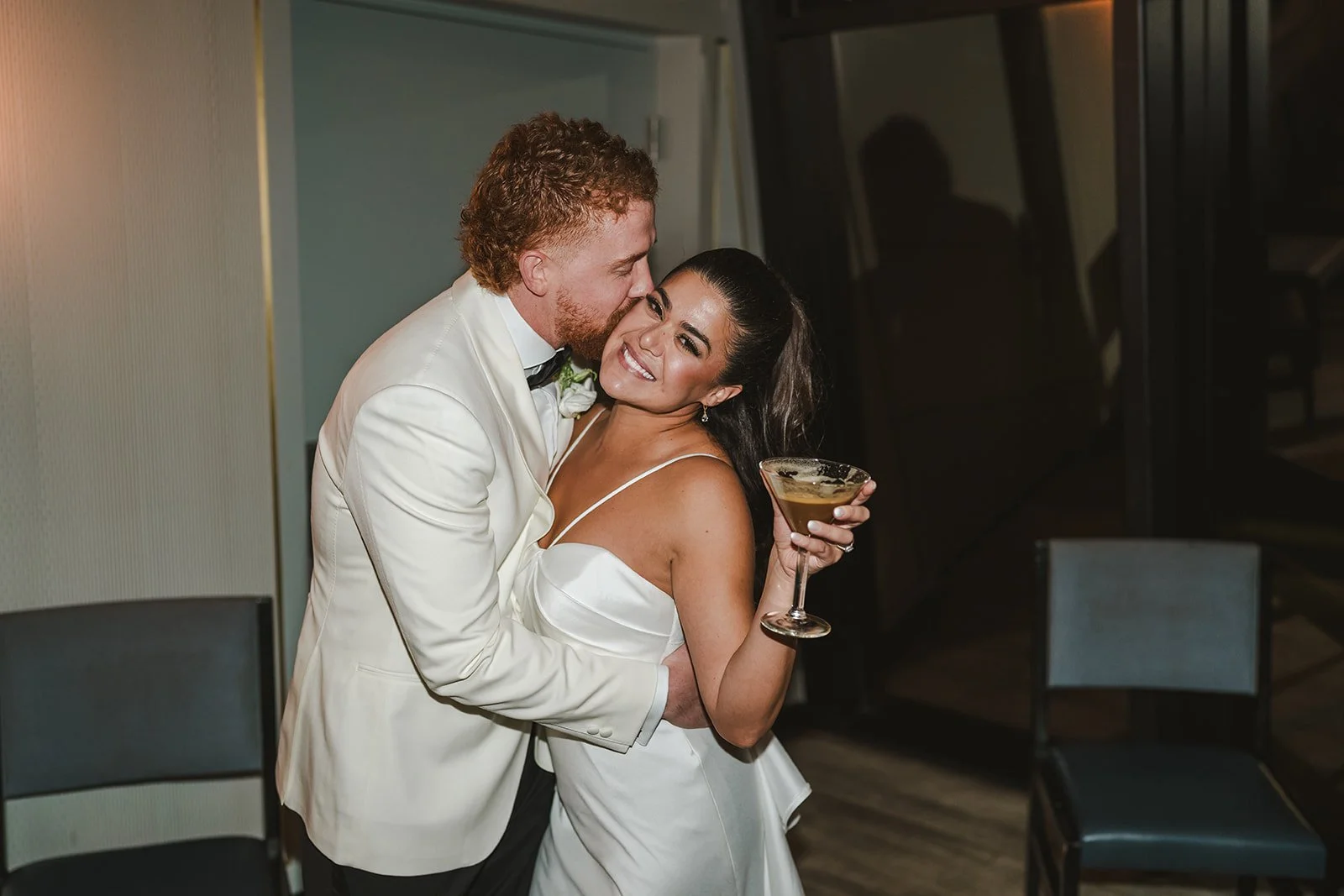 Groom kisses bride's cheek while she holds martini  Spencers at the waterfront  Pearle weddings  Burlington, ON  Fedora Media.jpg