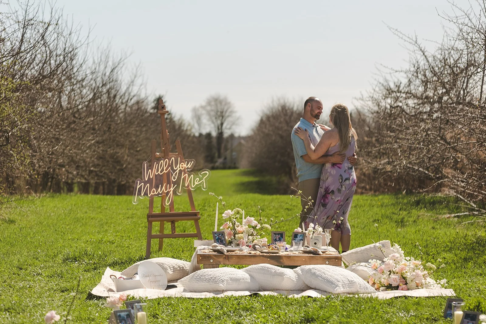 Couple embracing behind picnic set up  Orchard Propsal  Fedora Media.jpg