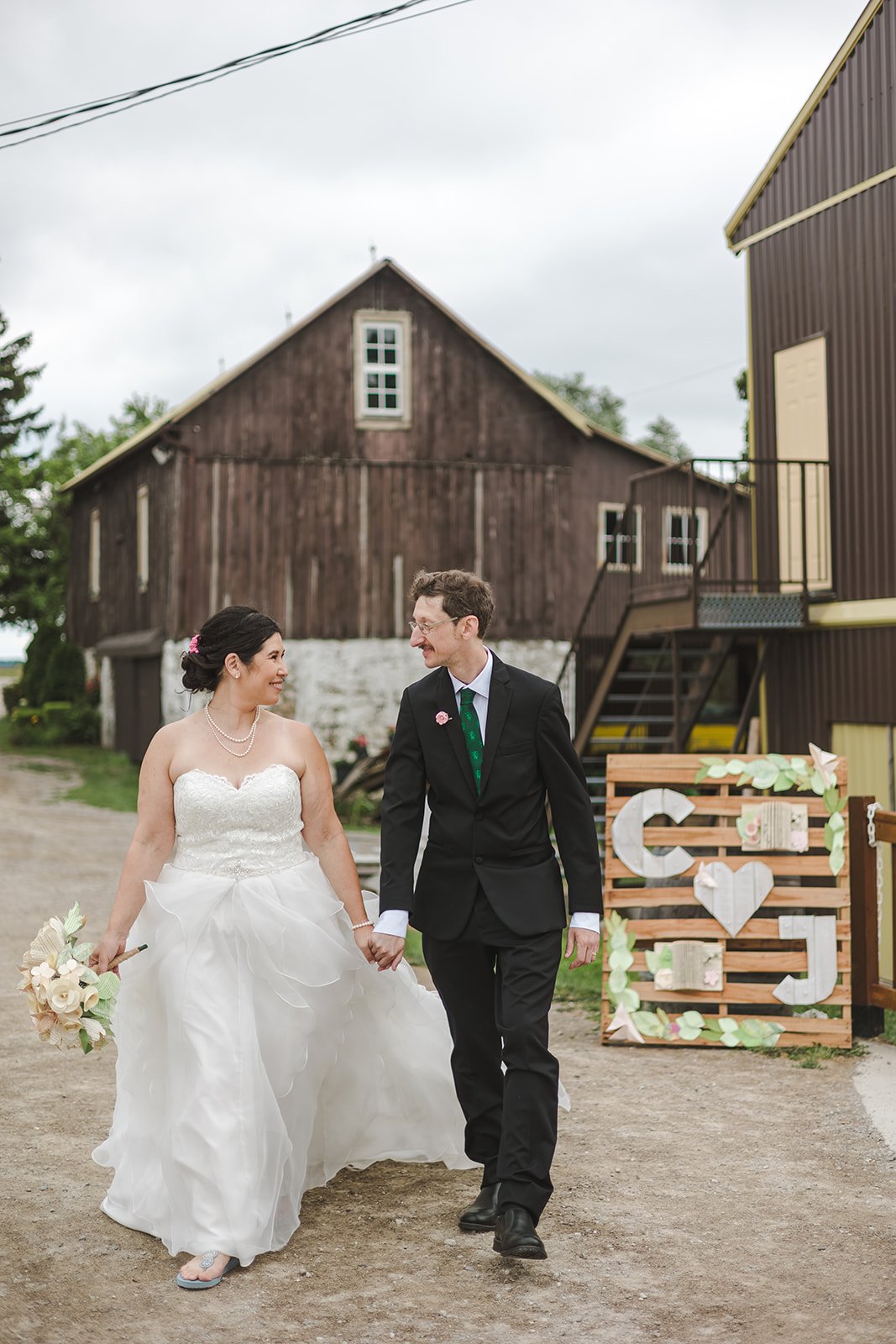 Bride and groom looking at each other walking past welcome sign  Hamilton, ON  Glen Drummond Farm  Fedora Media.jpg