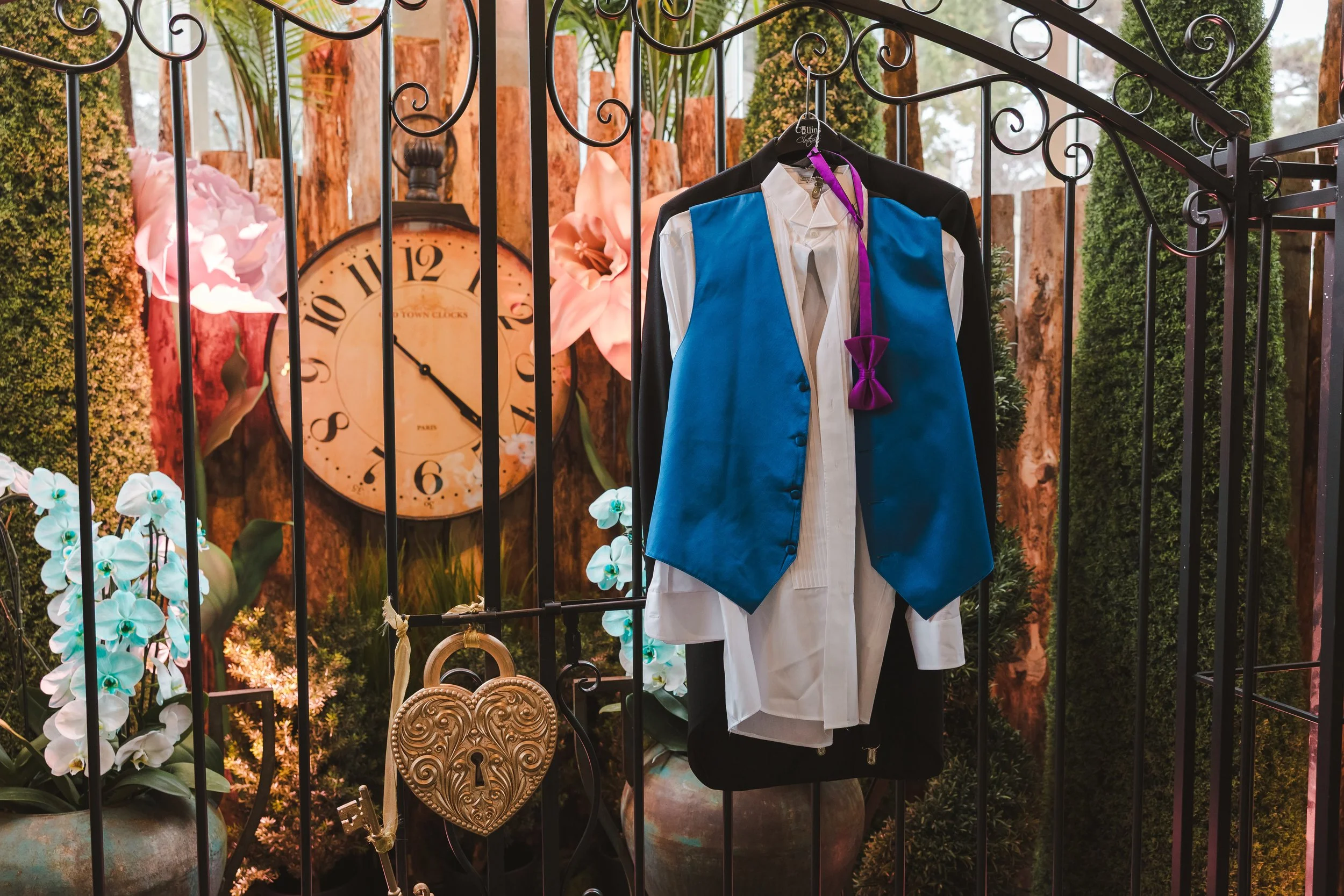 alice-in-bloomland-suit-hung-on-fence-in-front-of-clock-alice-in-bloomland-fedora-media.jpg
