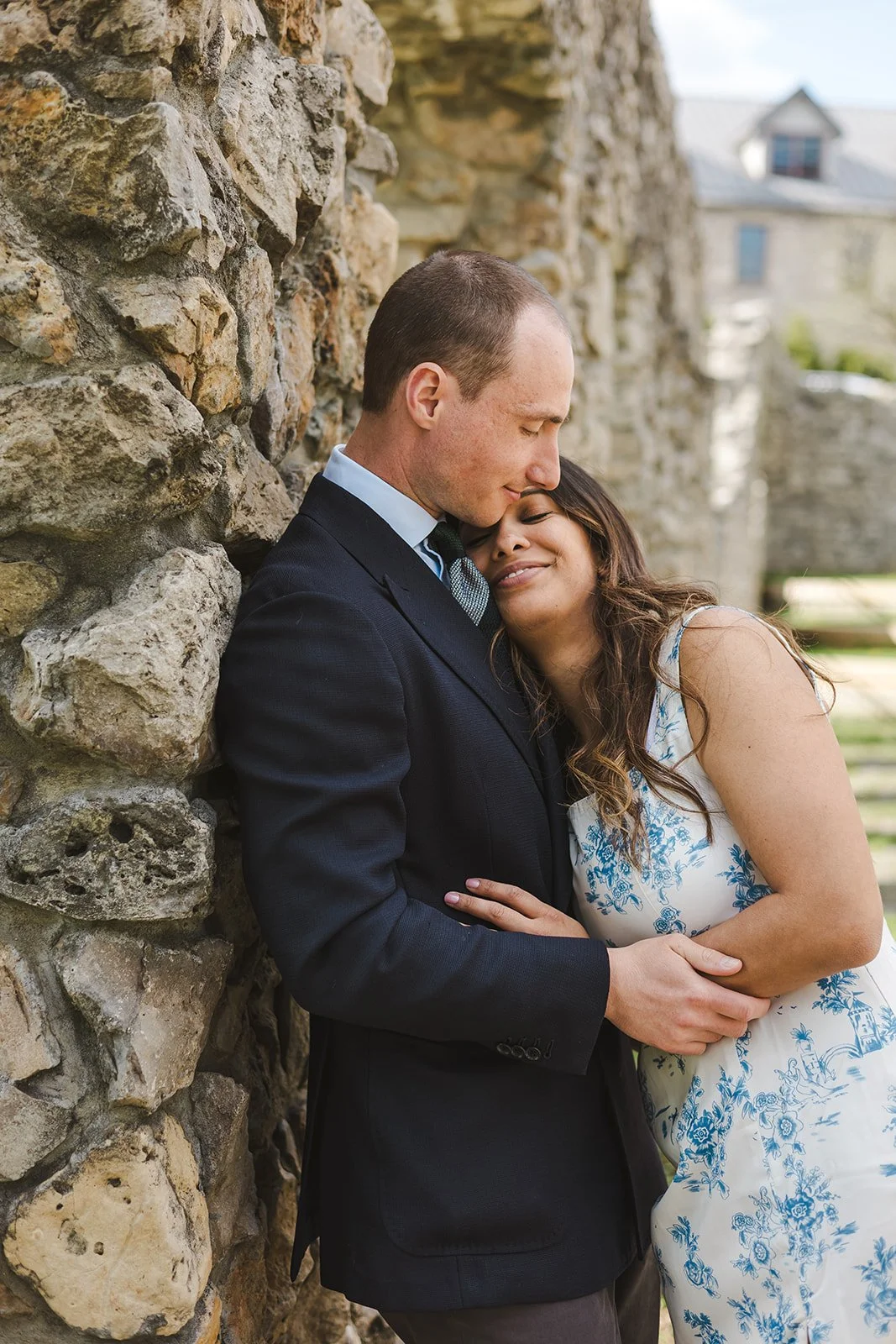 Couple embracing while leaning against stone wall  Ontario Engagement  Fedora Media.jpg