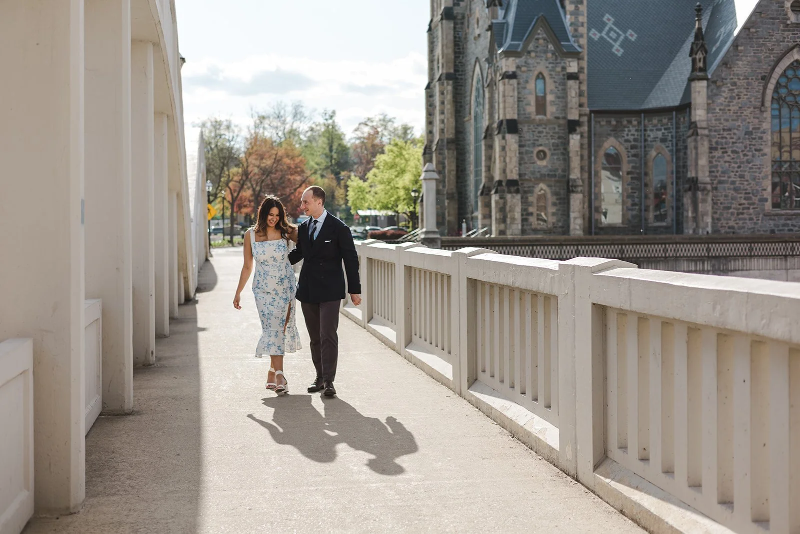 Couple walking on bridge in front of church  Ontario Engagement  Fedora Media.jpg