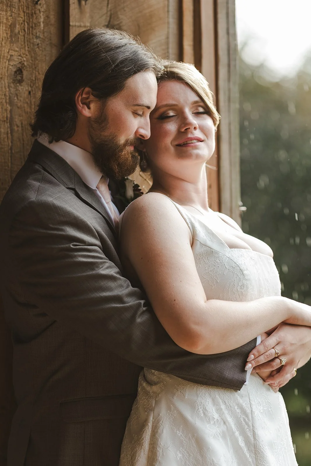 Bridge and groom embrace on rainey wedding day.jpg