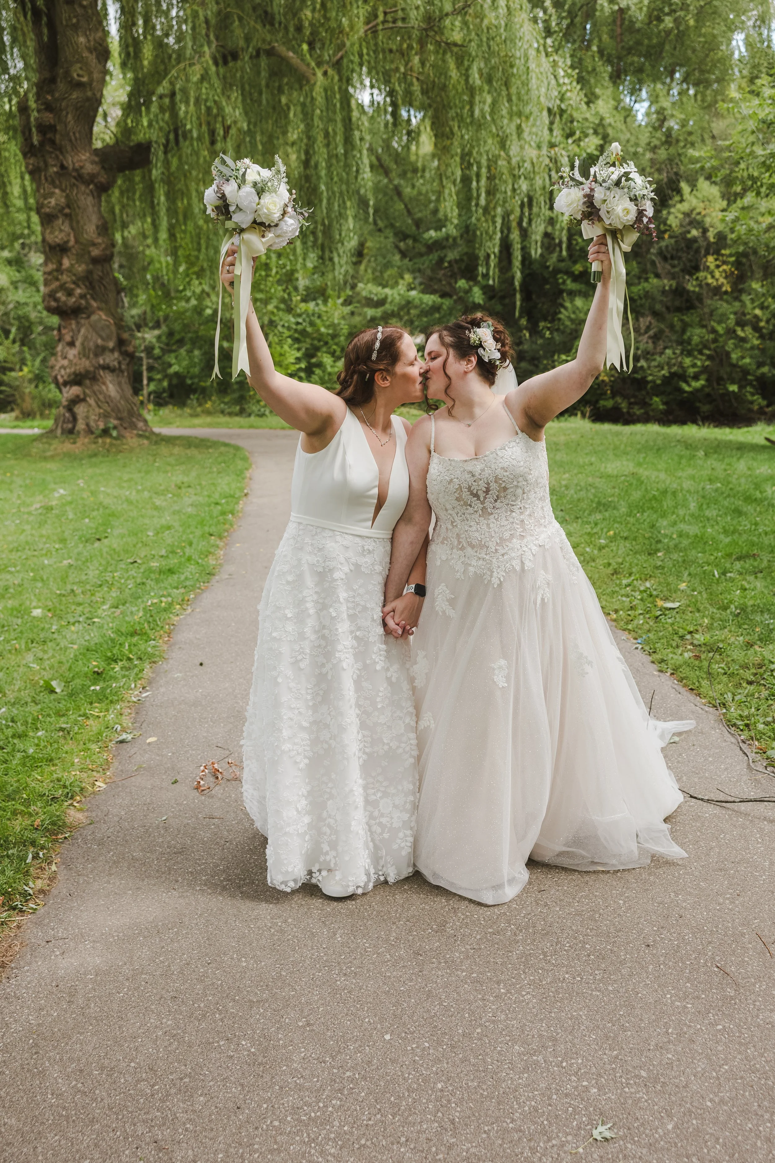 brides-kissing-holding-up-bouquet-on-path-newfoundlandclub-cambridge-ontario.jpg