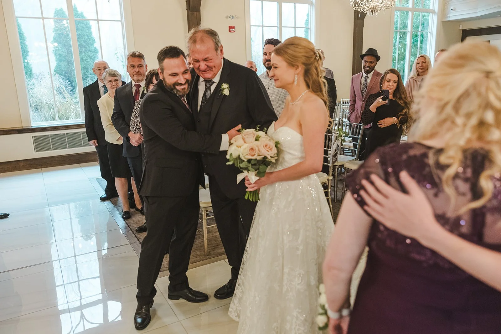 Groom hugs father in law during wedding ceremony  Ancaster,  ON  Ancaster Mill  Fedora Media.jpg