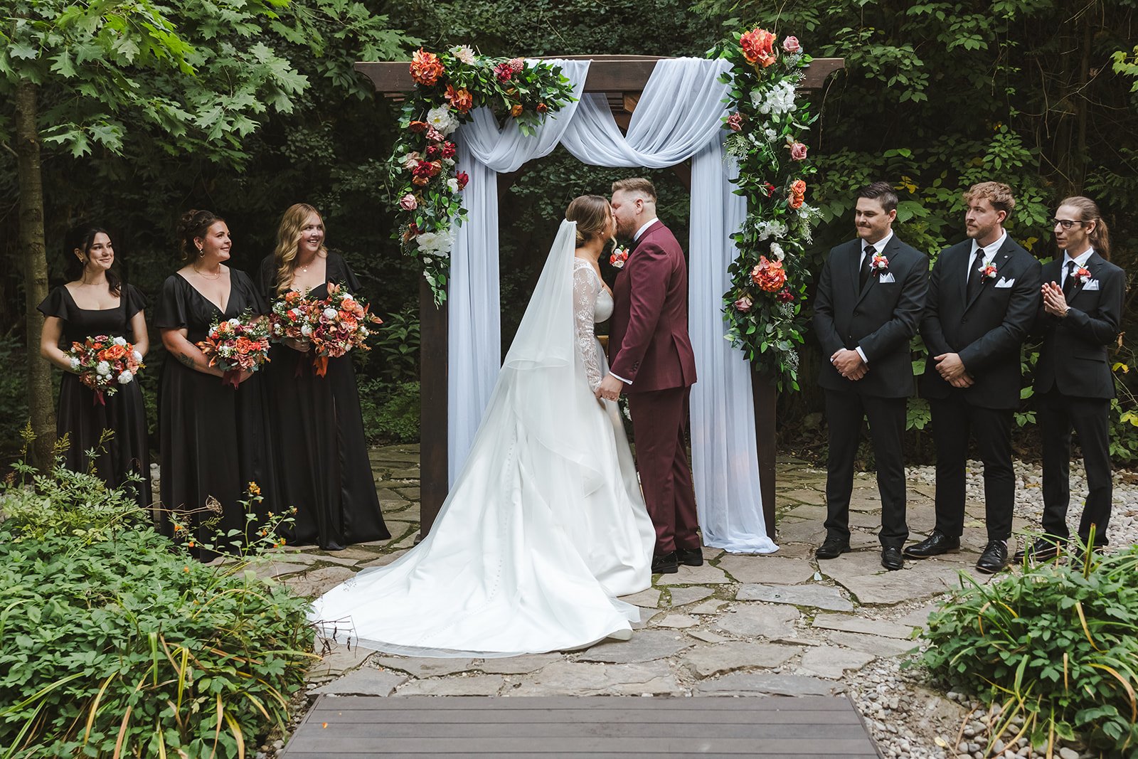 Wedding party watching bride and groom kiss at altar  Erin Estates  Fedora Media.jpg