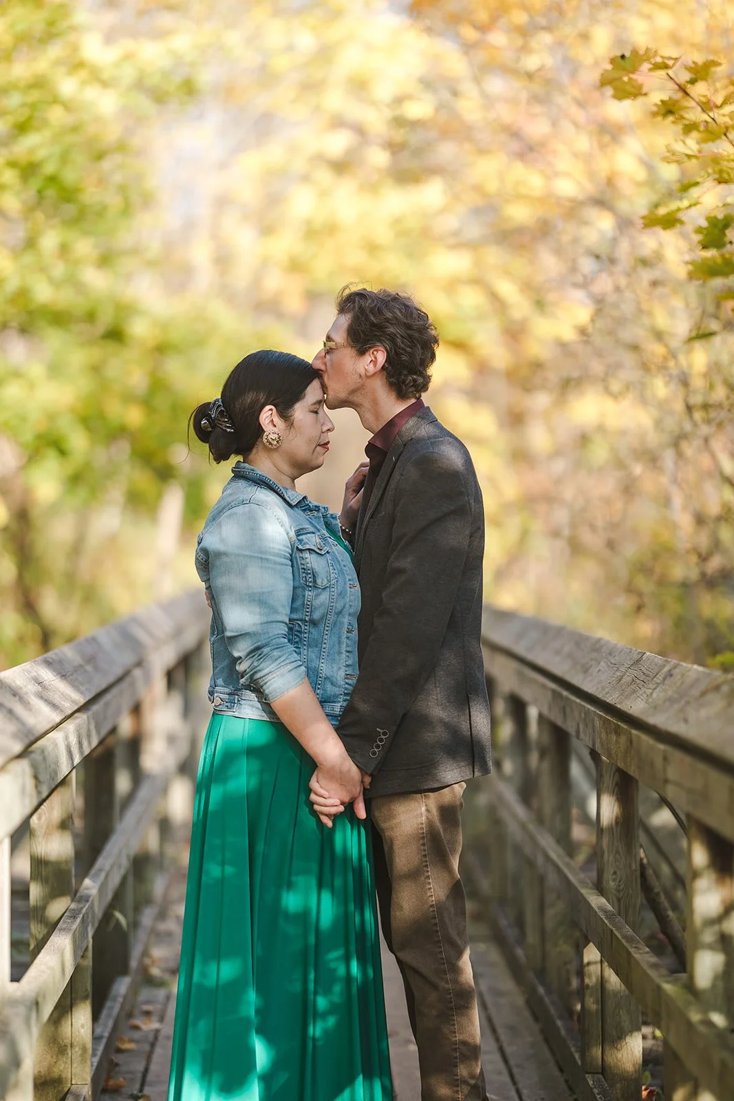 Man kissing woman's forehead on bridge  Ontario Engagement  Fedora Media.jpg