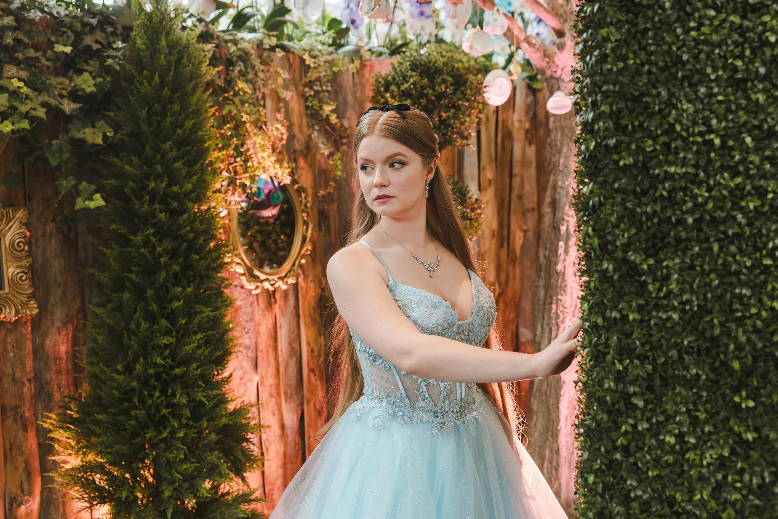 bride-in-blue-dress-standing-next-to-shrubs-alice-in-bloomland-fedora-media.jpg