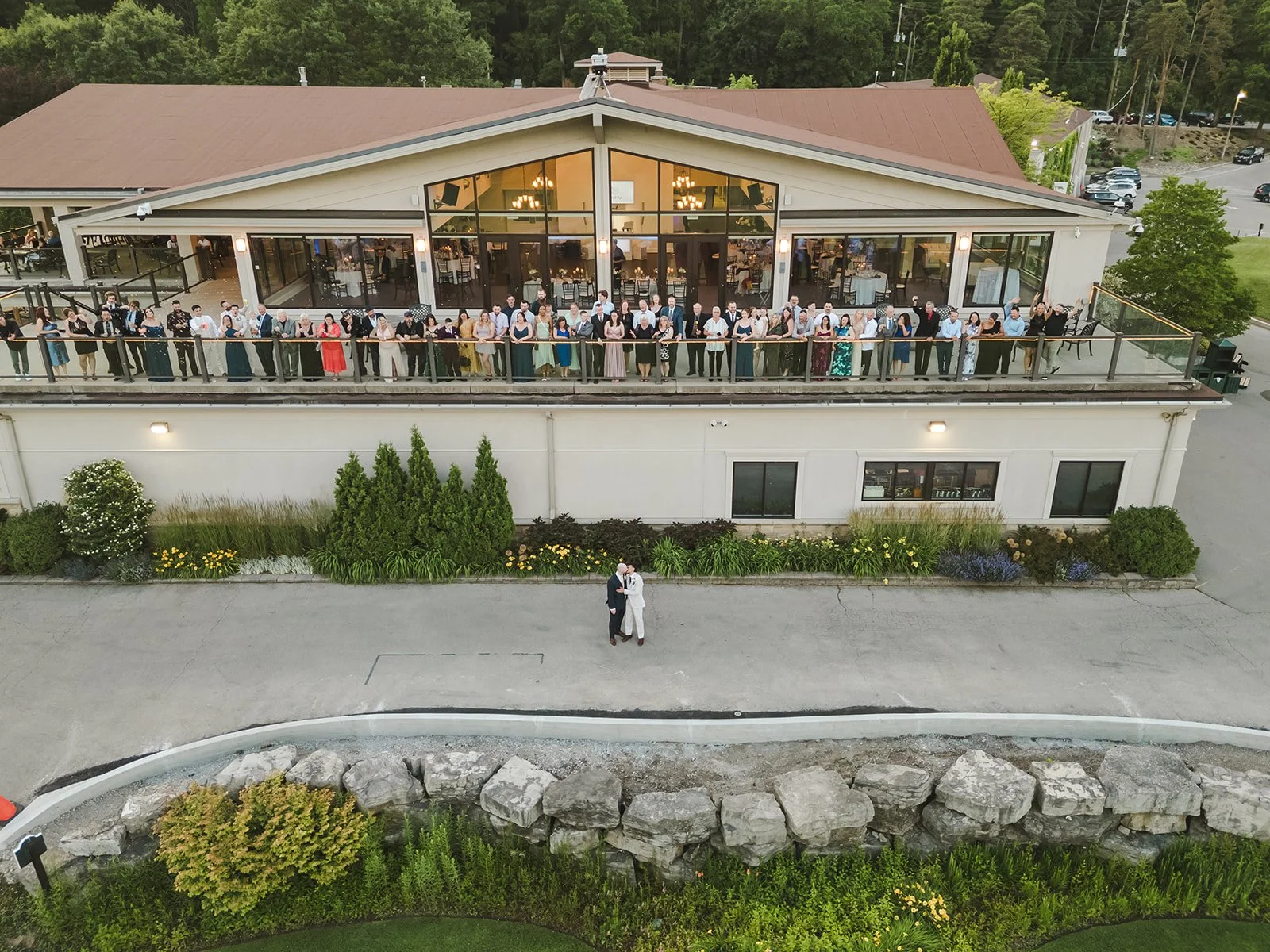 Grooms kiss with wedding guests on balcony  Dundas Valley  Fedora Media.jpg