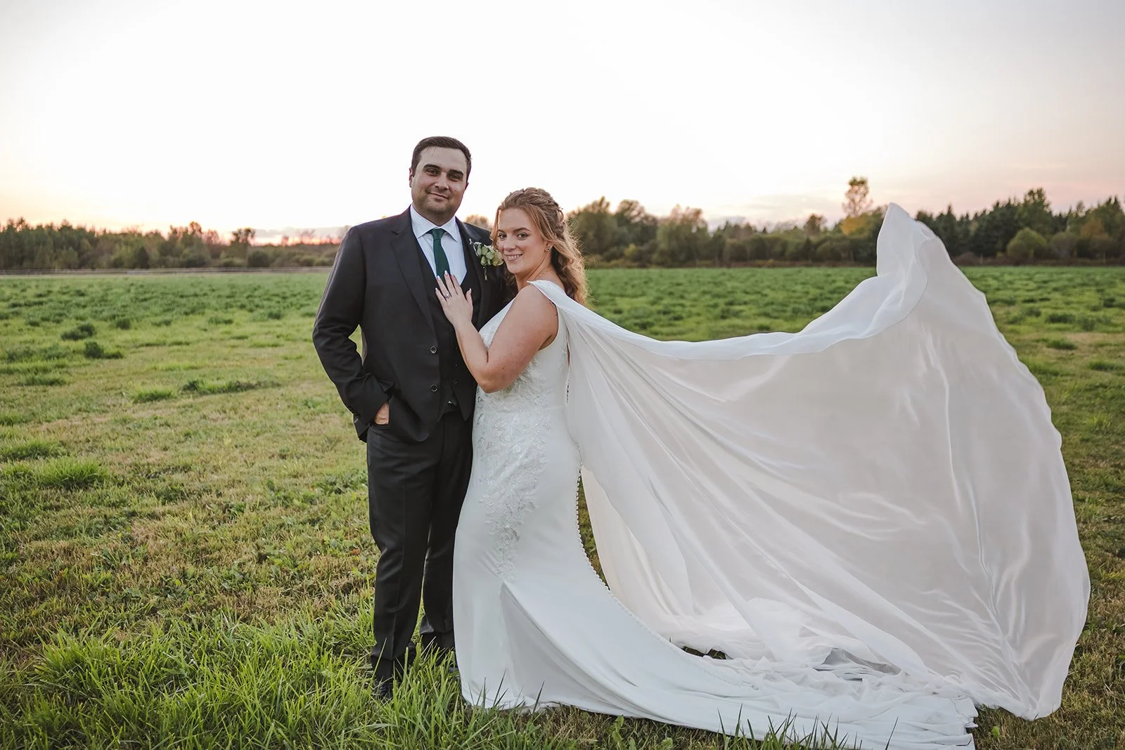 Bride and groom standing in field with flowing cape  Erin Estates  Fedora Media .jpg