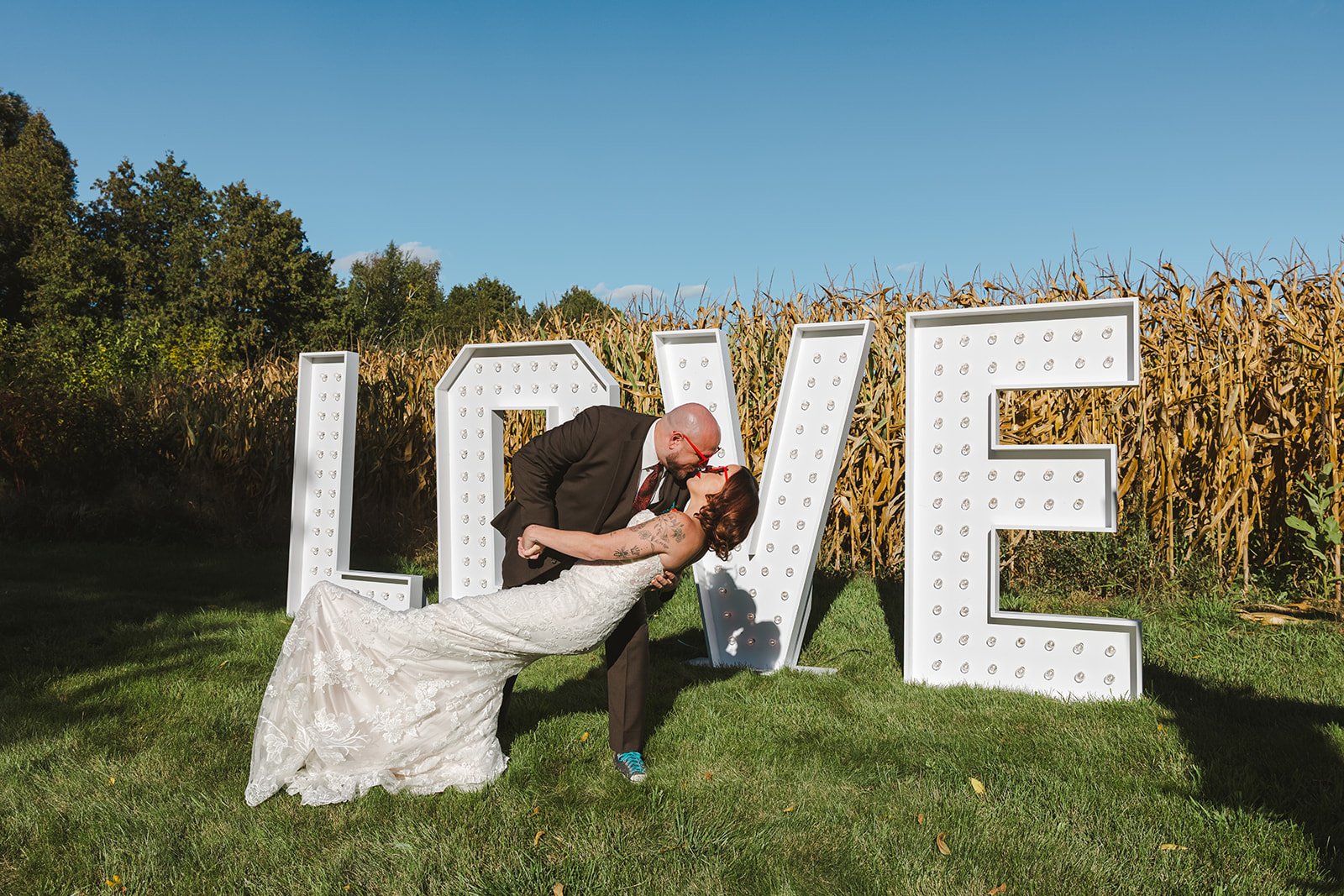 Bride and Groom Dip Kiss in front of love sign  Great Lakes Helicopters  Fedora Media.jpg