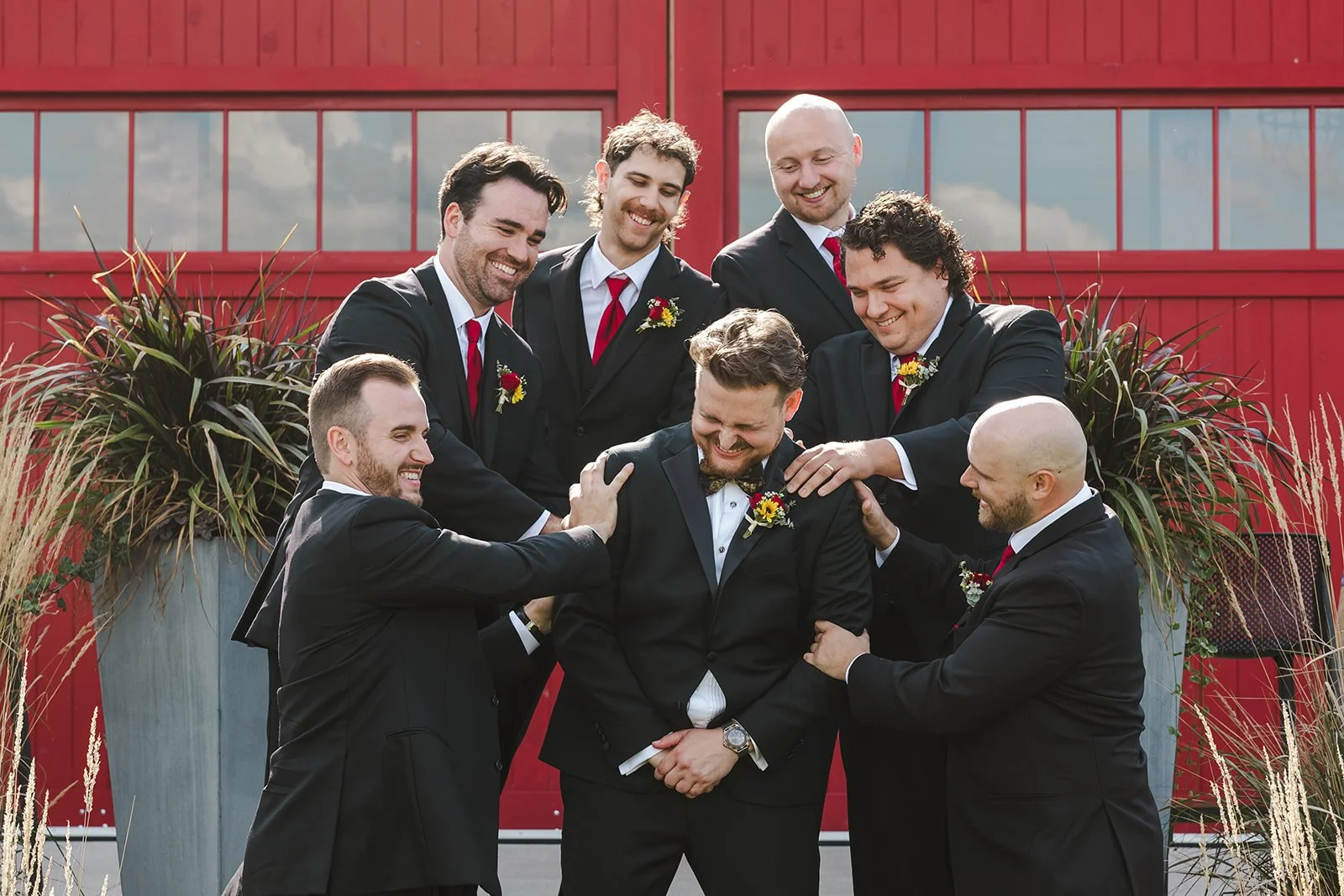 Groomsmen huddled around groom  Barn Swallows at Thatcher Farm  Fedora Media.jpg