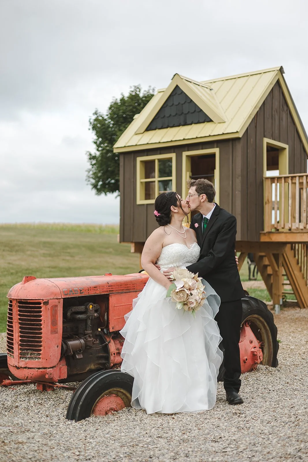 Bride and groom kissing in front of tractor and treehouse  Hamilton, ON  Glen Drummond Farm  Fedora Media .jpg