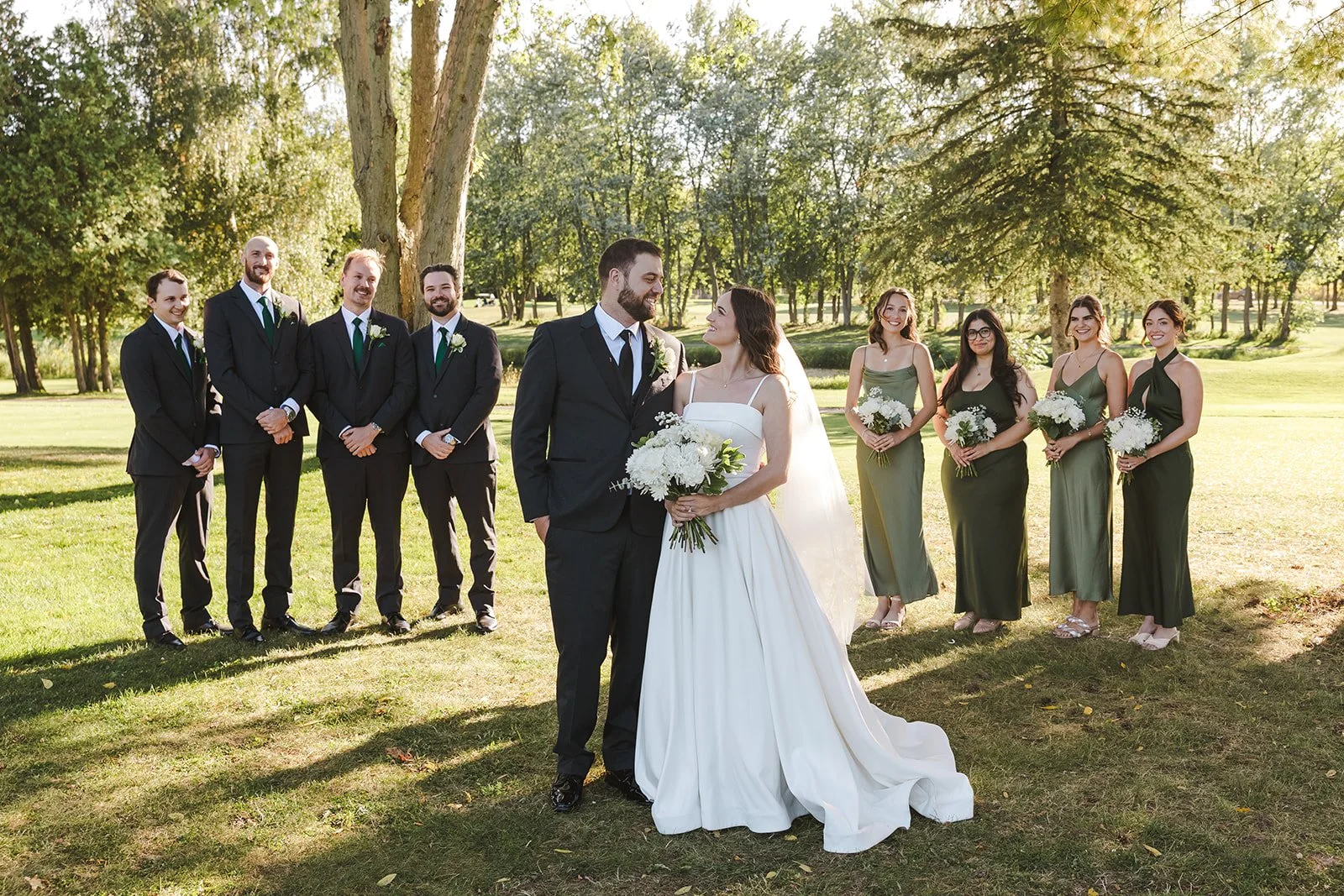 Bride and groom looking at each other surrounded by wedding party Century Pines  Fedora Media.jpg