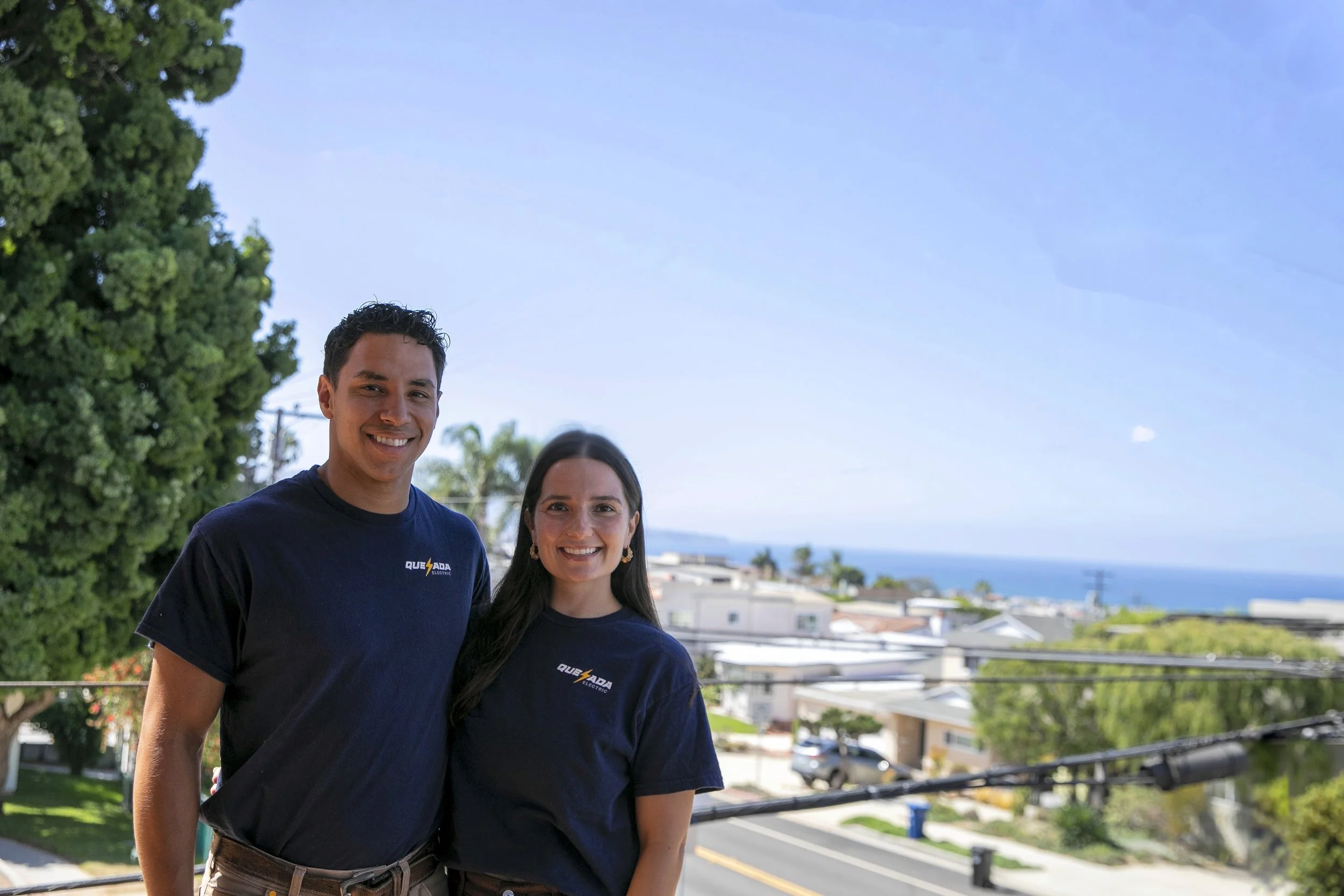 Quesada Electric owners Samir and Bridget Quesada in company shirts overlooking Hermosa Beach.