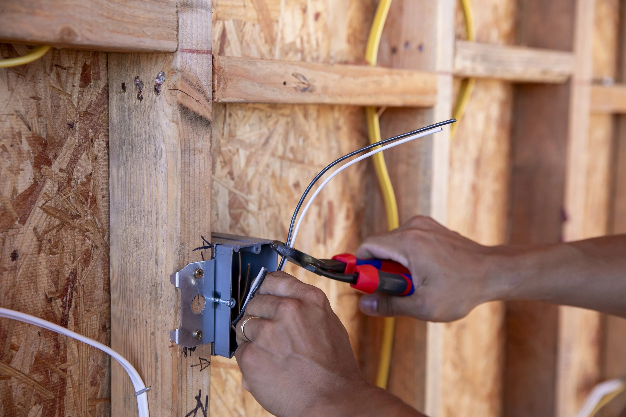 Electrician securing wires to metal electrical box with pliers