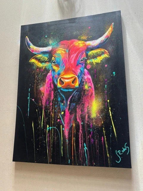 Colorful neon-style painting of a bull with bright colors on a black background.