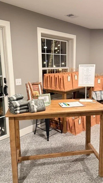 Table with wrapped gifts and a framed picture in a room with grey walls and a window.