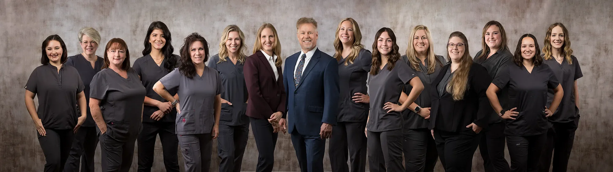 Group photo of fourteen healthcare professionals, including doctors and nurses, standing side by side in business casual attire against a neutral background.