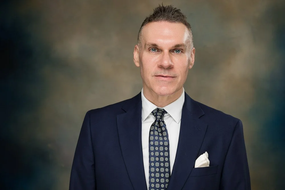 business man in suit and navy blue sportcoat in front of marbled backdrop