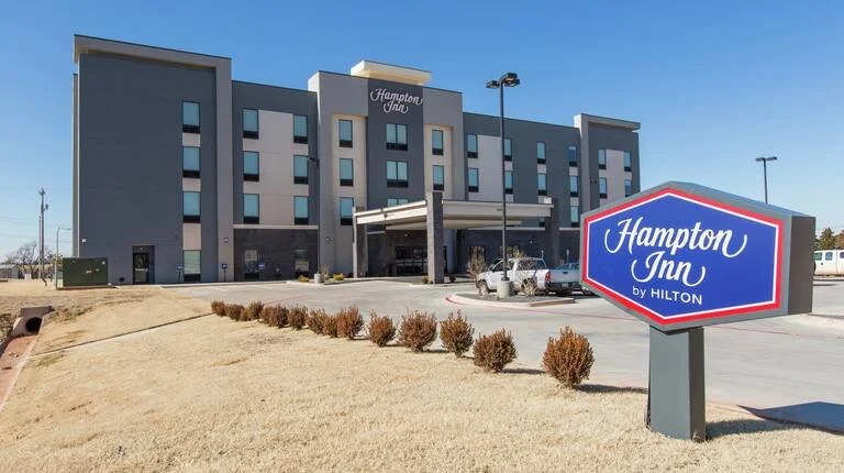 Front view of a Hampton Inn by Hilton hotel with a large sign in the foreground.