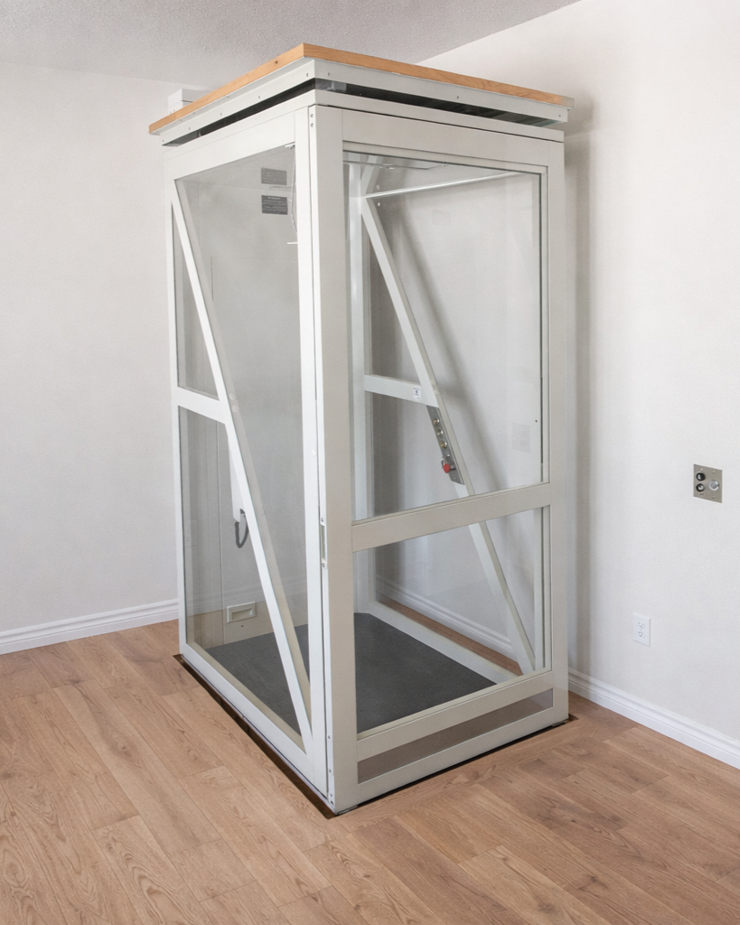 Elevador de cristal en una pared blanca, con estructura de metal blanca y suelo de madera.