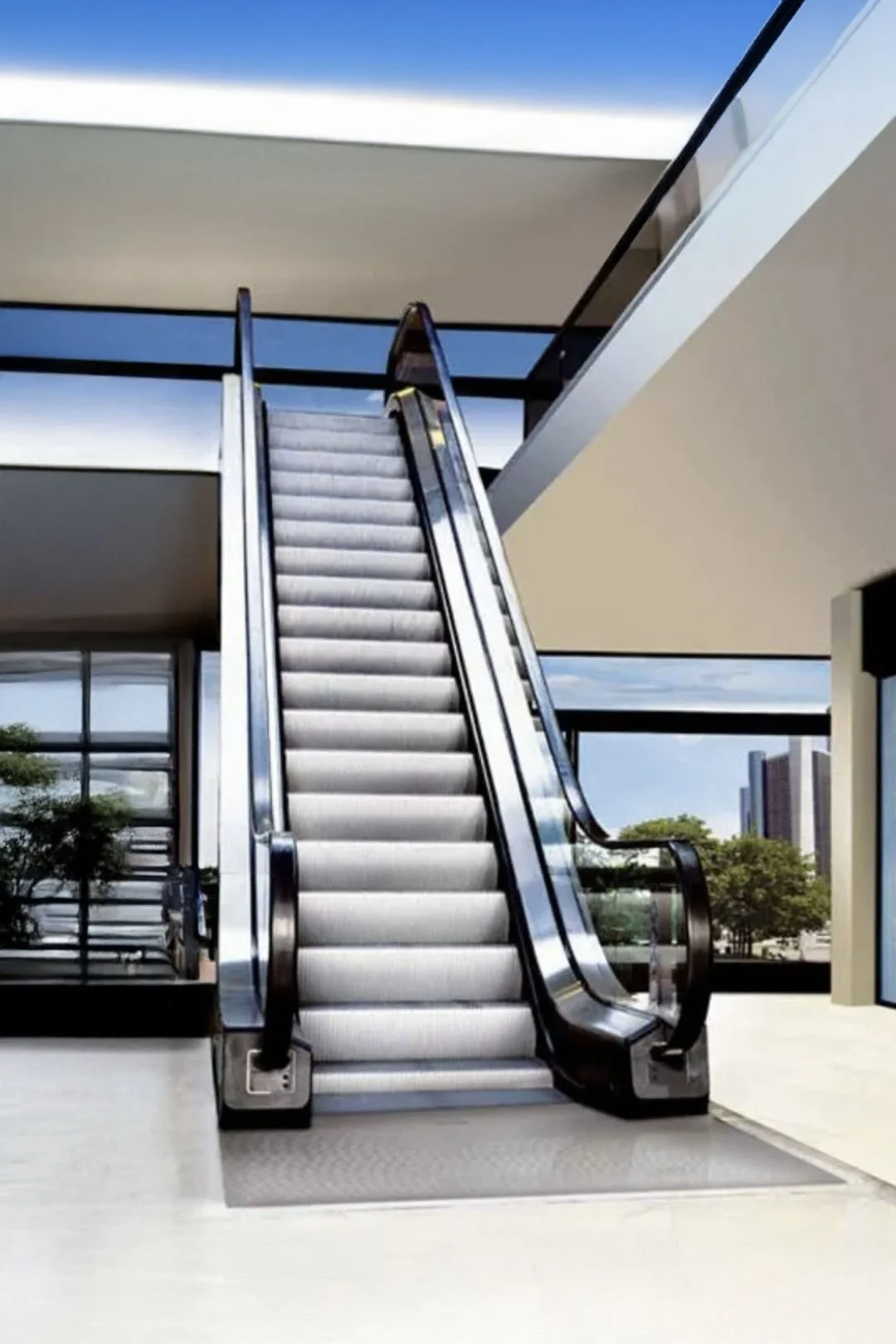 Escalera eléctrica en un edificio moderno con vistas a la ciudad y cielo azul.