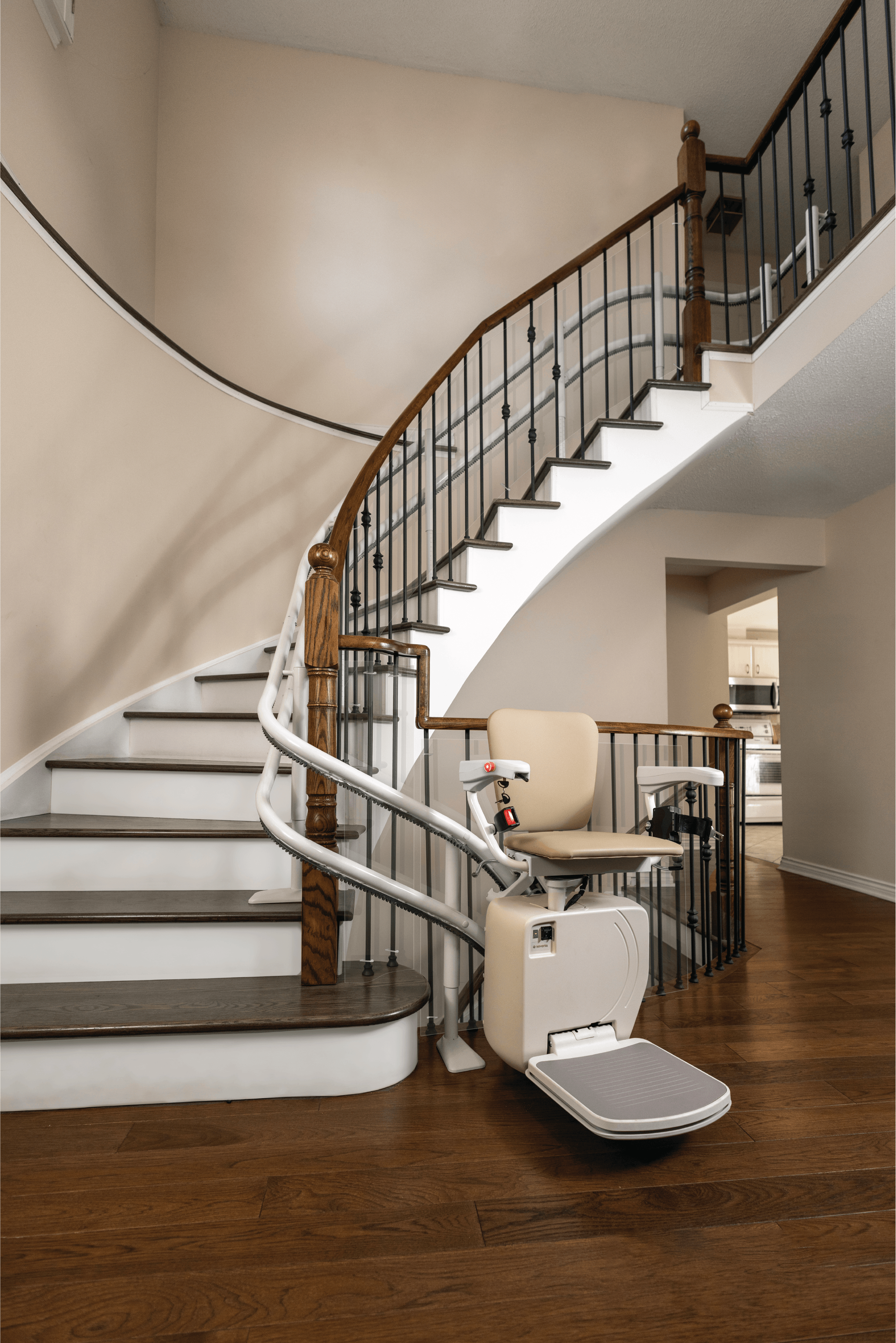 Silla de ruedas eléctrica junto a la escalera en interior de casa con suelo de madera.