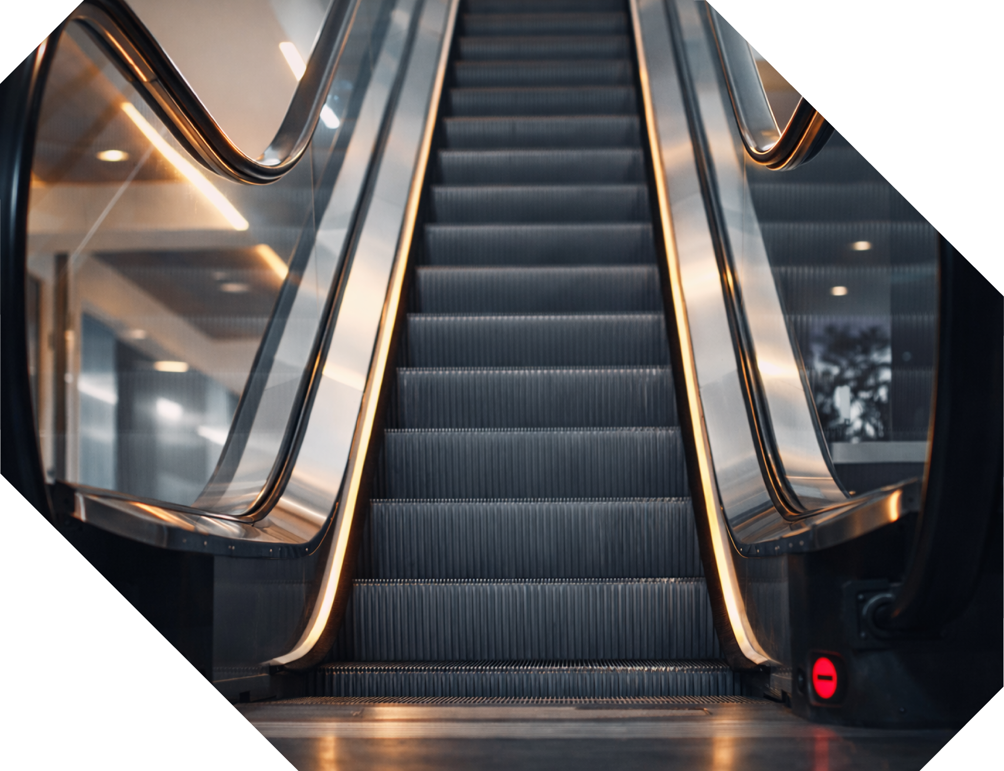 Escalera mecánica en un centro comercial o edificio moderno, con barandillas de metal y luces en los bordes.