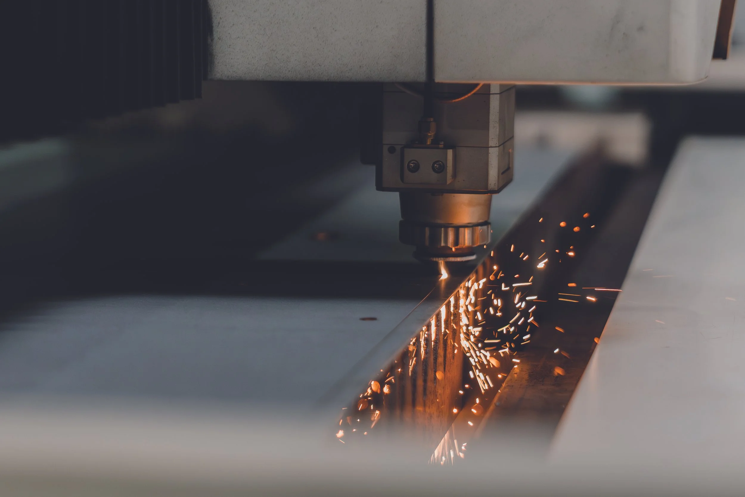 Una máquina de corte por láser en proceso, con chispas saltando mientras corta metal.