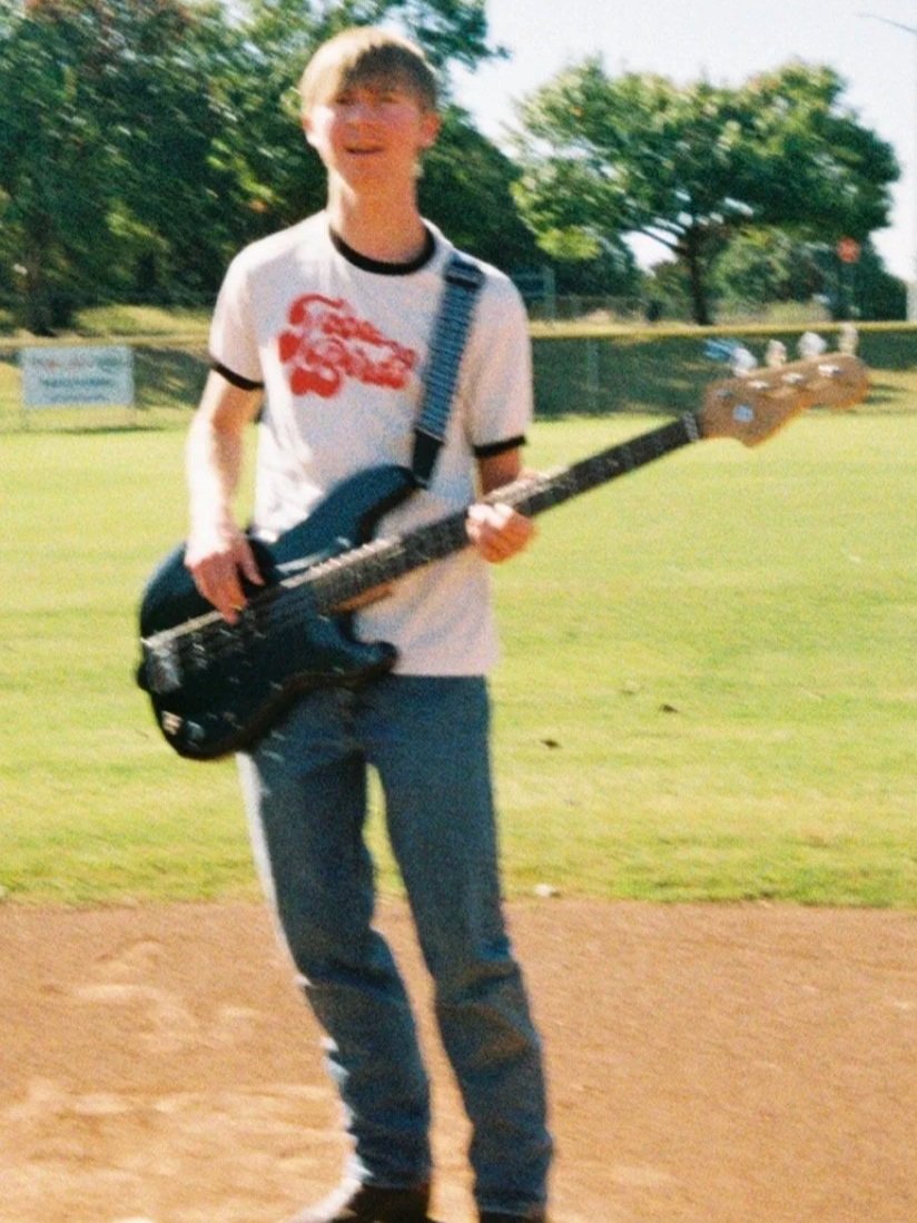 Manse Jones playing the bass guitar in a baseball field (February 2026). Photo credit to Rania Geraghty. | Denton's premiere cosmic country band. 'Cosmic American Music' available on all streaming platforms. LPs/CDs. Flying since 2024!