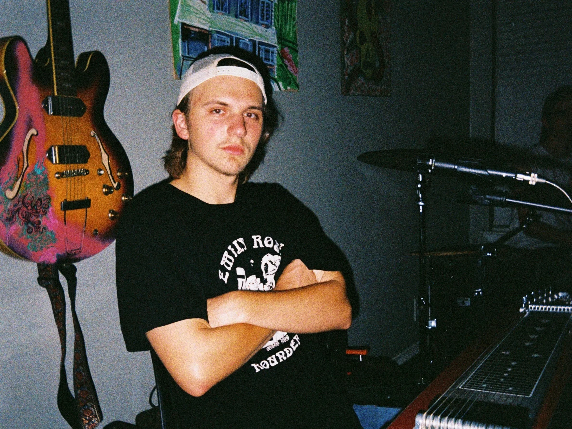 Jake Bullman with his arms crossed and cap backwards, looking cross. Photo credit to Chris Smith. | The Tabasco Birds, Denton's premiere cosmic country band. 'Cosmic American Music' available on all streaming platforms. LPs/CDs. Flying since 2024!