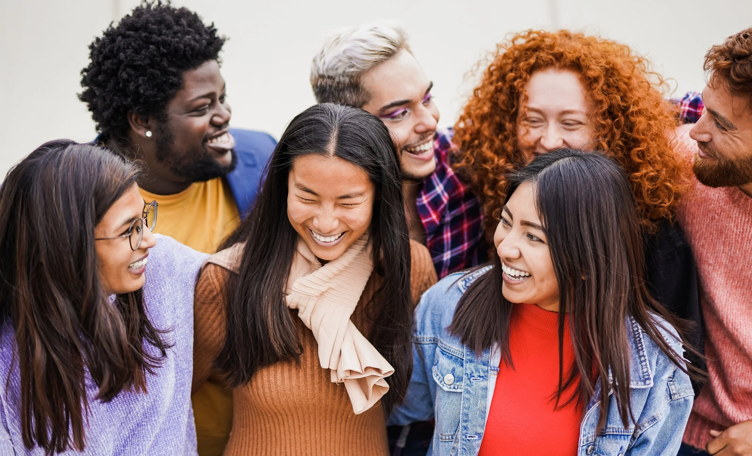 Group of diverse young people smiling and laughing close together.