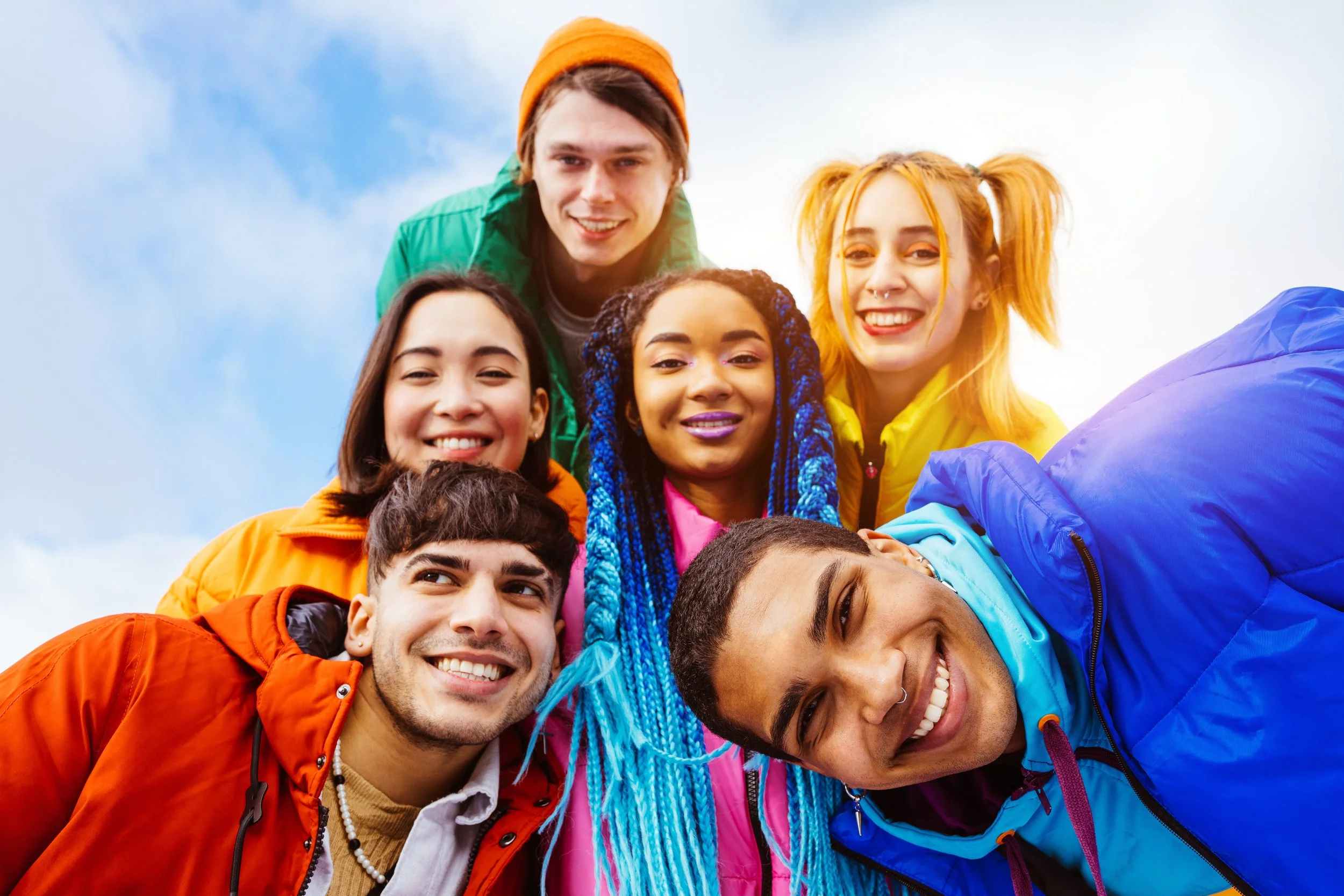 Group of 6 teenagers wearing colorful jackets and smiling