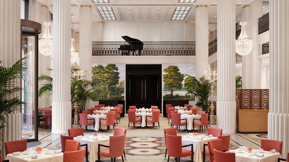 Elegant restaurant interior with round tables, pink chairs, large white columns, greenery, and a grand piano