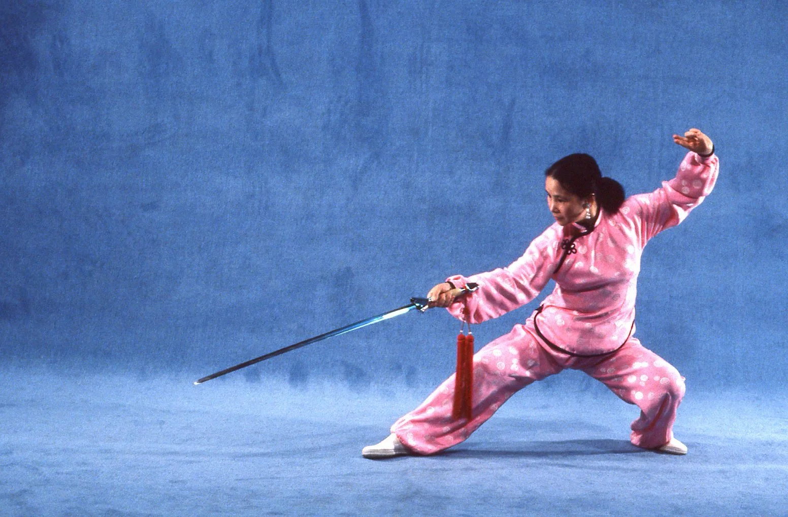 Grandmaster Bow Sim Mark striking a traditional Chinese sword pose in pink martial arts attire.