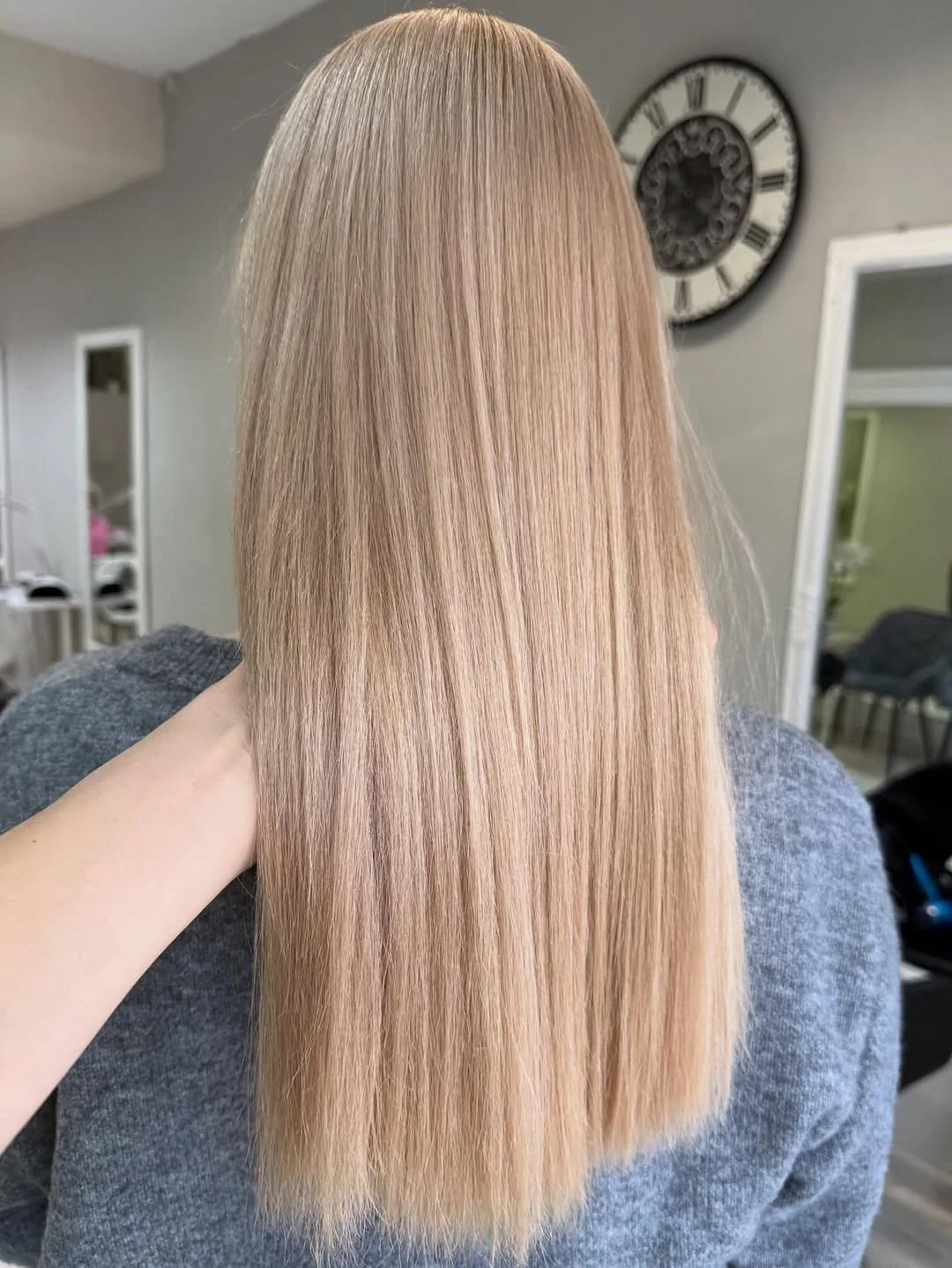 Ilgi, tiesūs šviesūs plaukai salono aplinkoje.