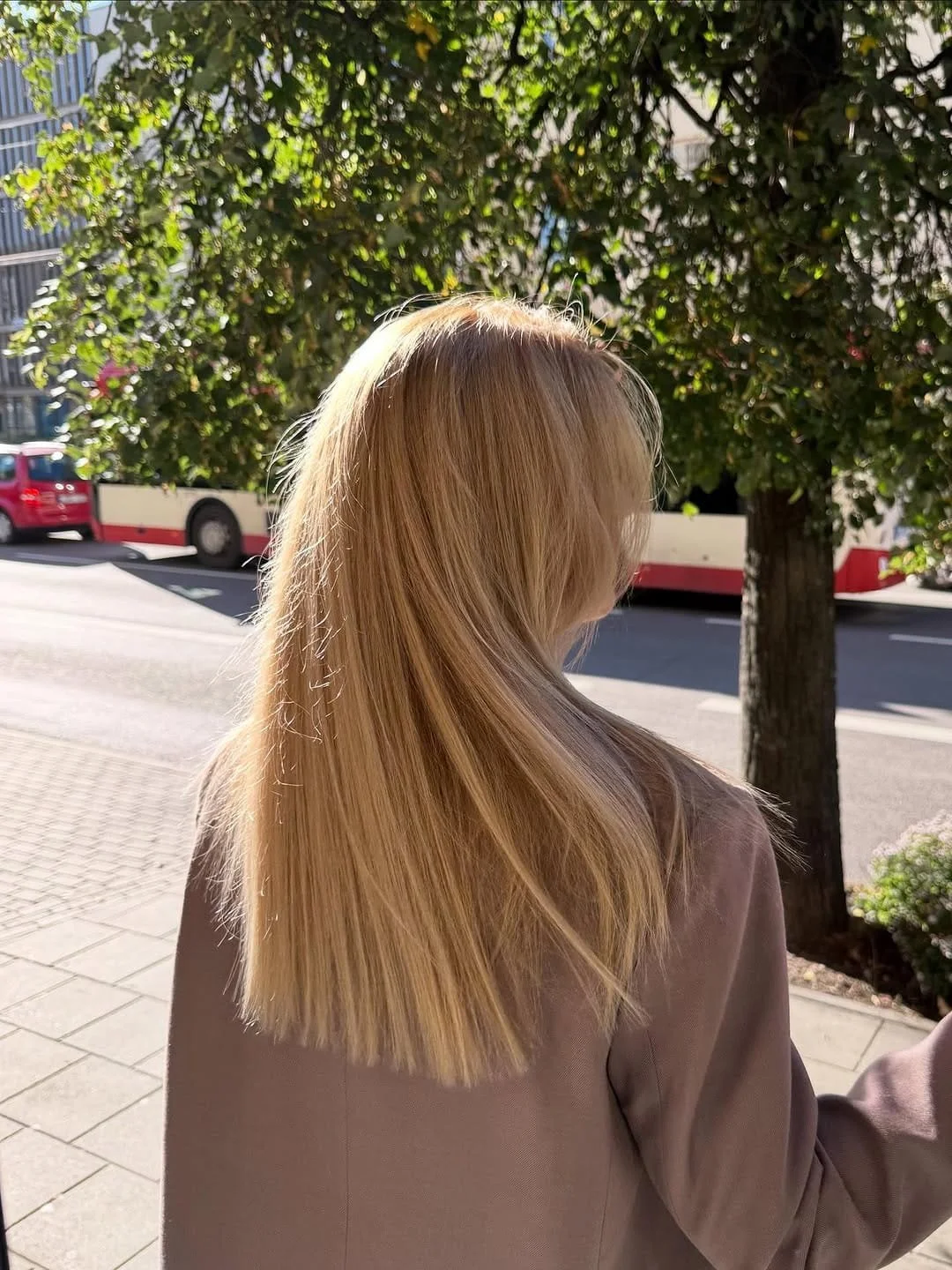 Moteris ilgais šviesiais plaukais stovinti mieste, vaizdas iš nugaros.