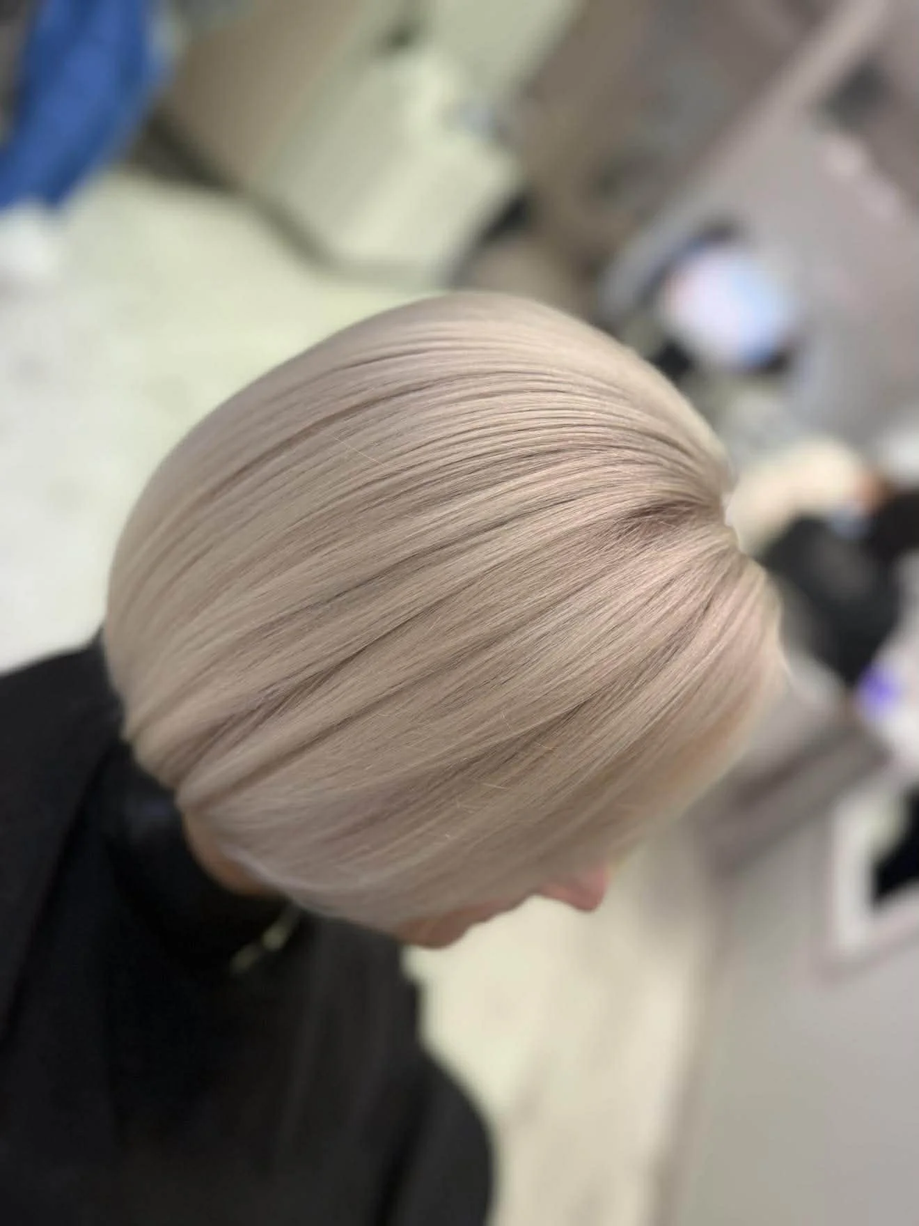 Stilingas platininės blondinės „bob“ kirpimas salone.