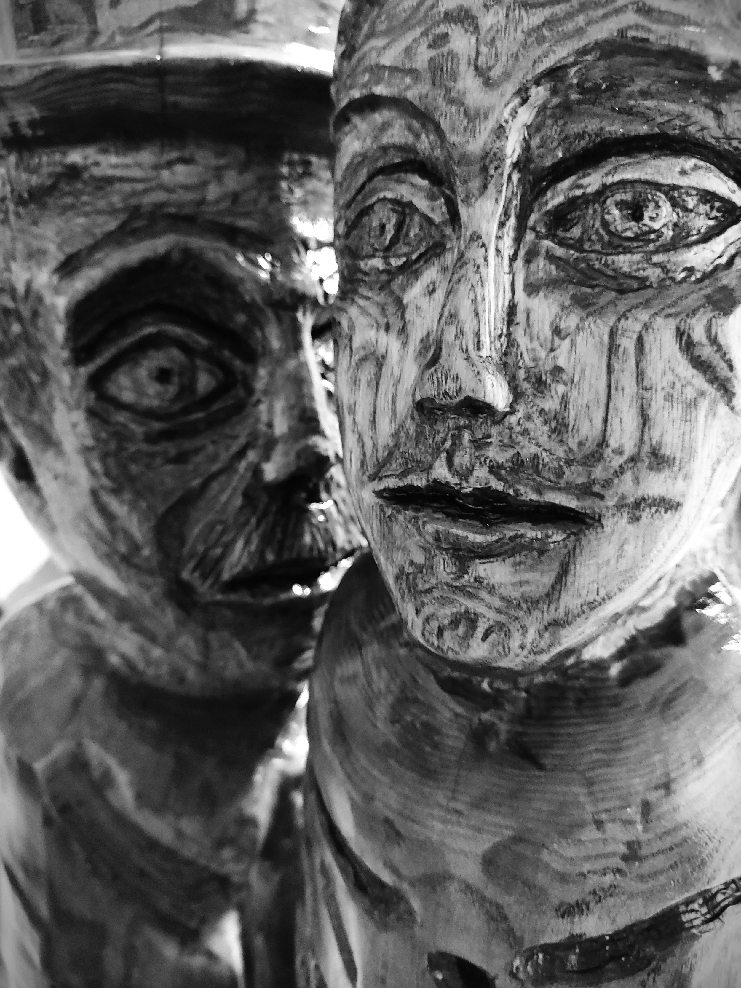 A close-up of carved wood depicting a human face with detailed features and expressive eyes.