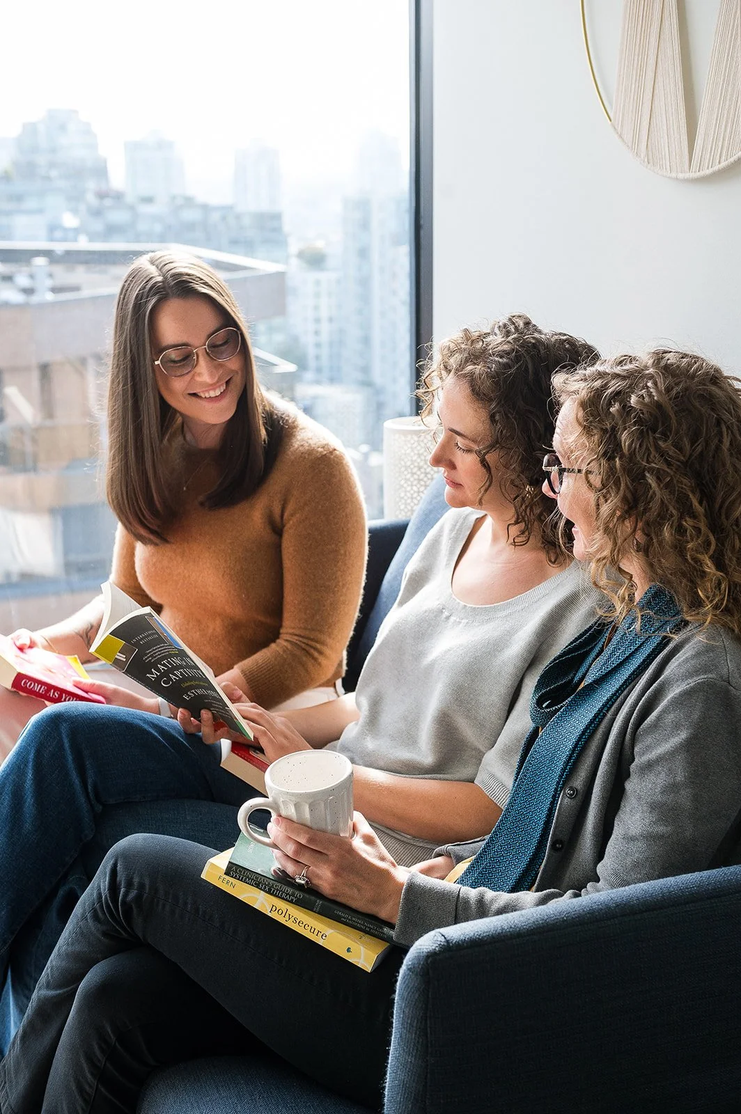 Three Women Counsellors Vancouver City Scape Window Discussing Online Group Therapy In Canada