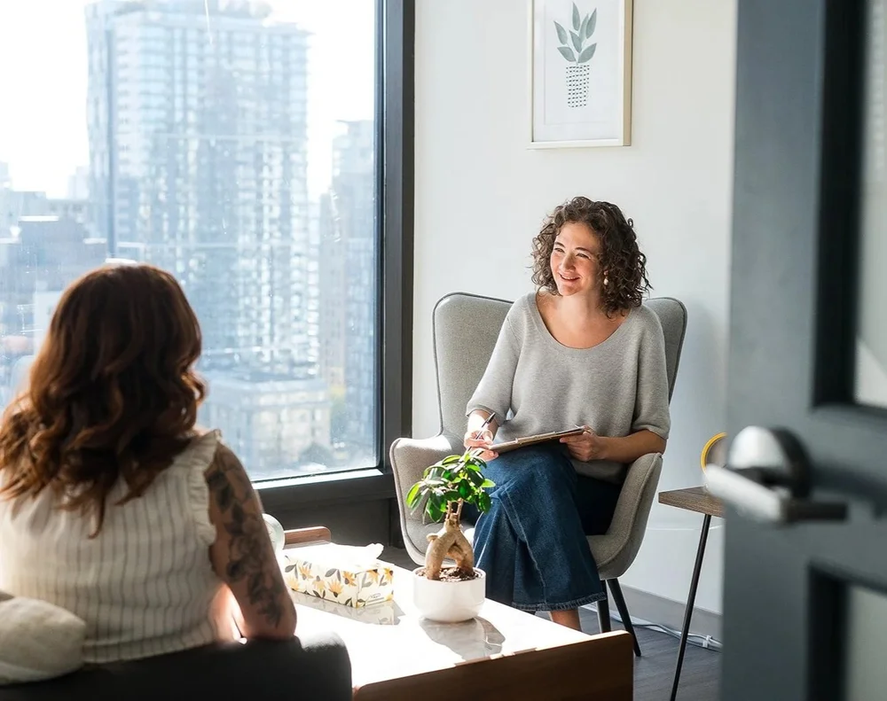 A counsellor and client talking in a bright Allura counselling room.