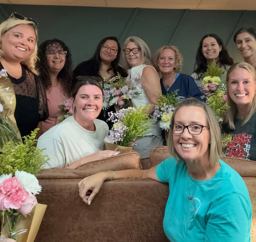 Nicole Mayo, founder of The Soul Space, with women from the community holding flowers at the café in Panama City