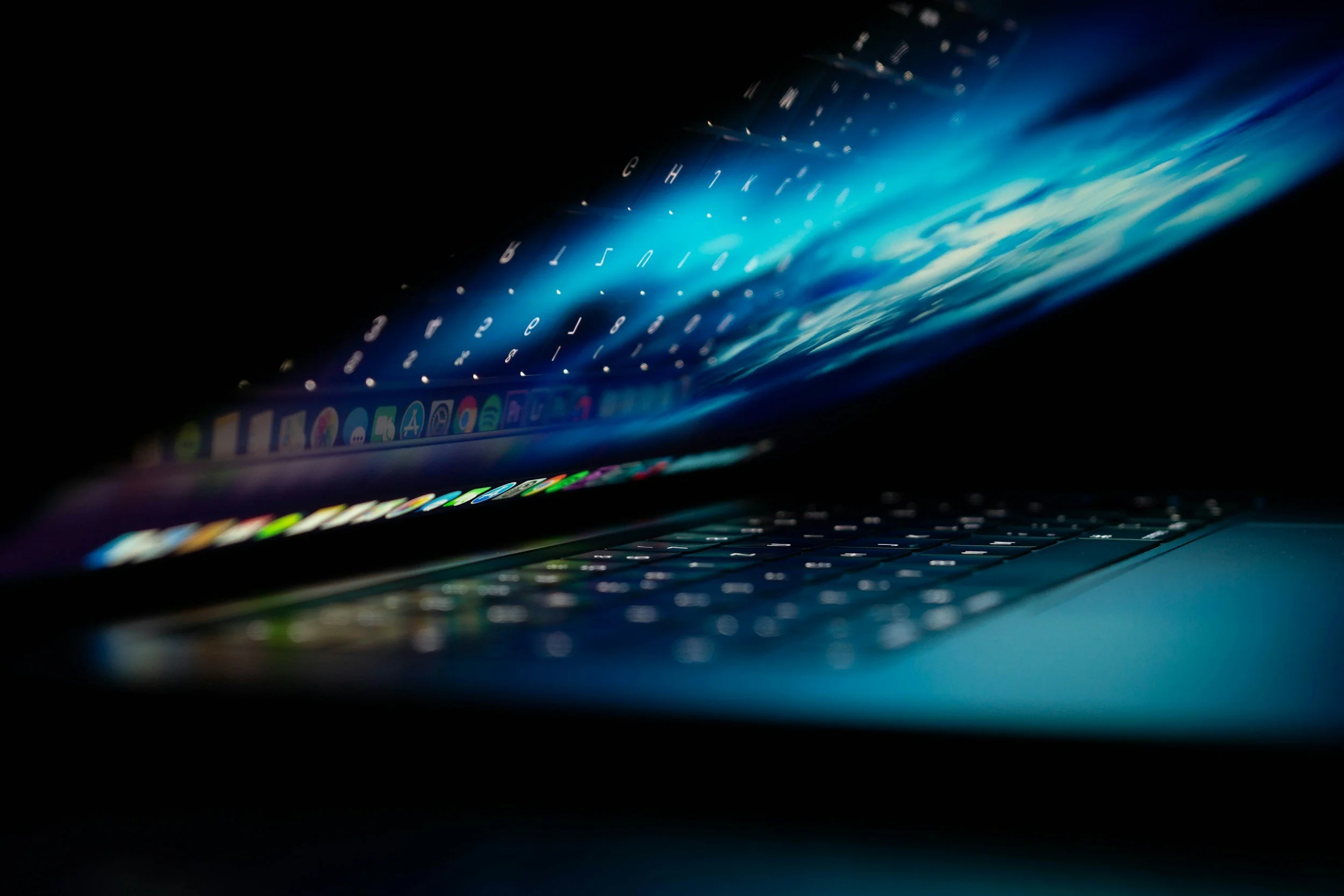 High-end laptop glowing with blue light in a dark room, representing computer support services for Boston-based consumers and businesses.