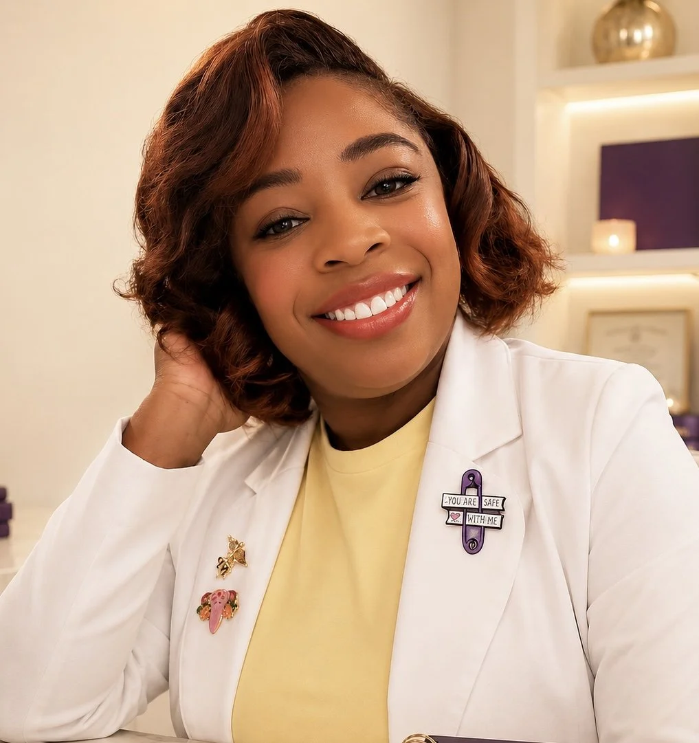 A smiling woman with short curly hair, wearing a white coat with pins, sitting in a room decorated with candles and shelves.